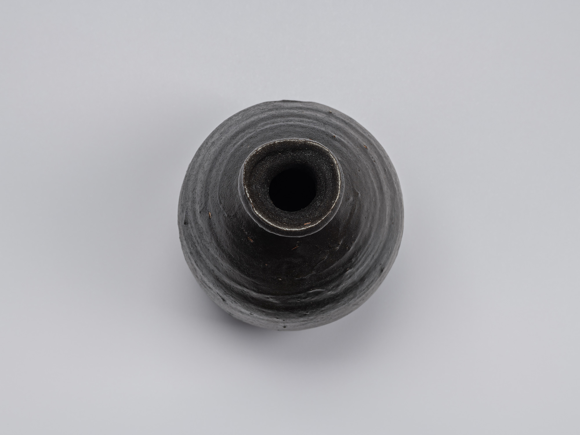 Overhead view of the Kuro Tokkuri by Shiro Tsujimura, showing the irregular rounded mouth, thick...