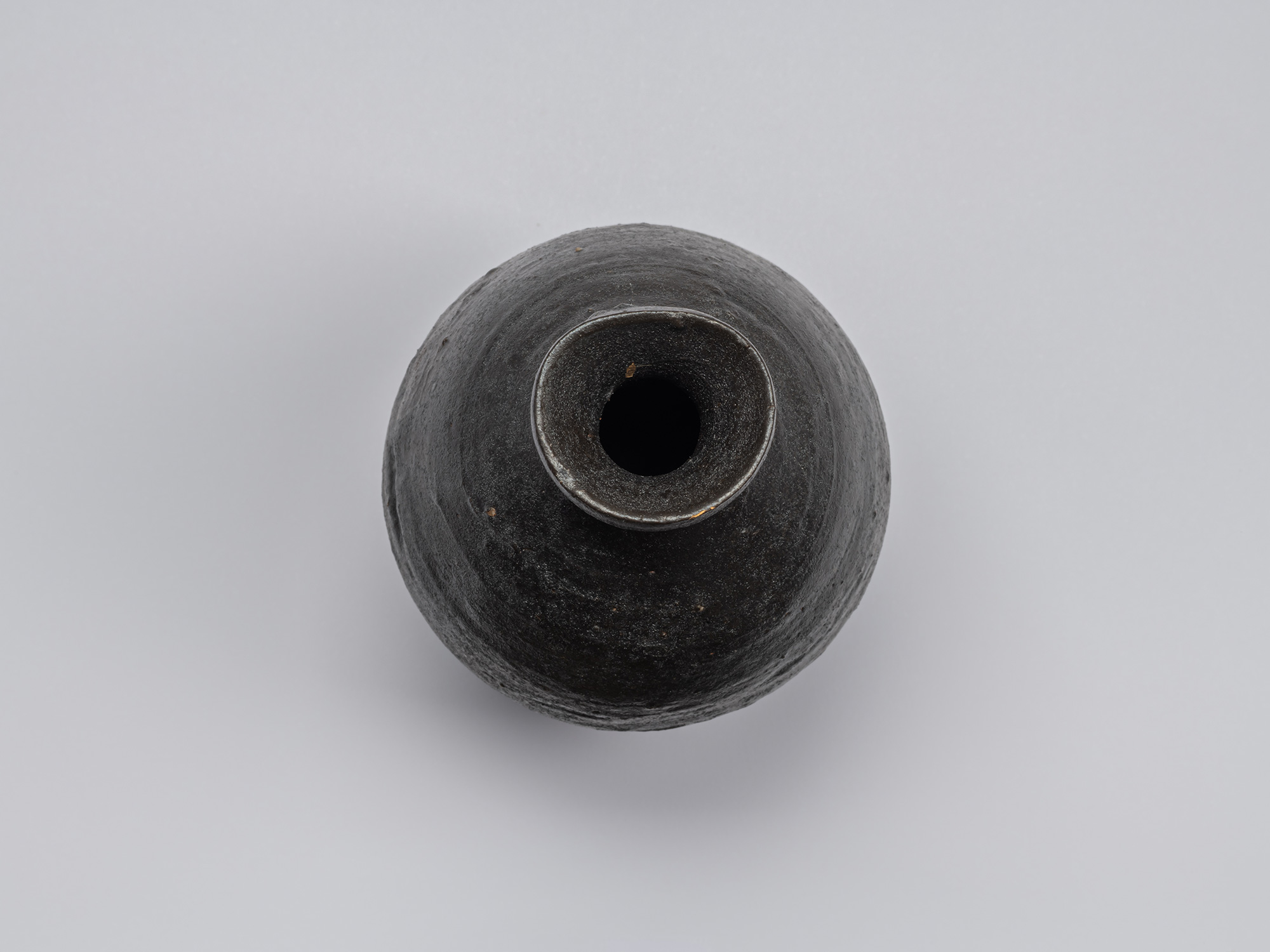Overhead view of the Kuro Tokkuri by Shiro Tsujimura, showing the irregular rounded mouth, thick...