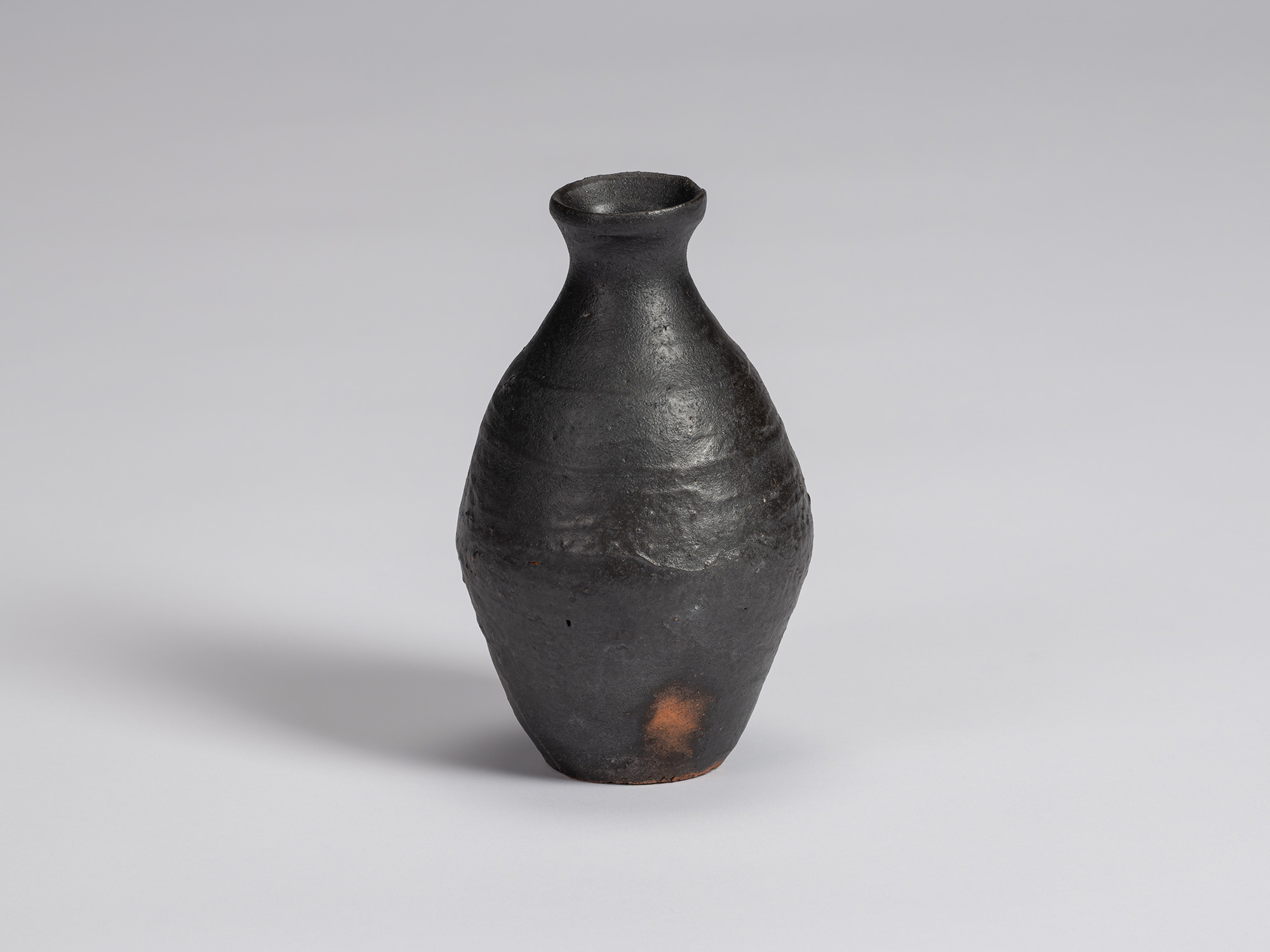 Kuro Tokkuri by Shiro Tsujimura, with an elongated rounded body, narrow neck, and irregular flared...