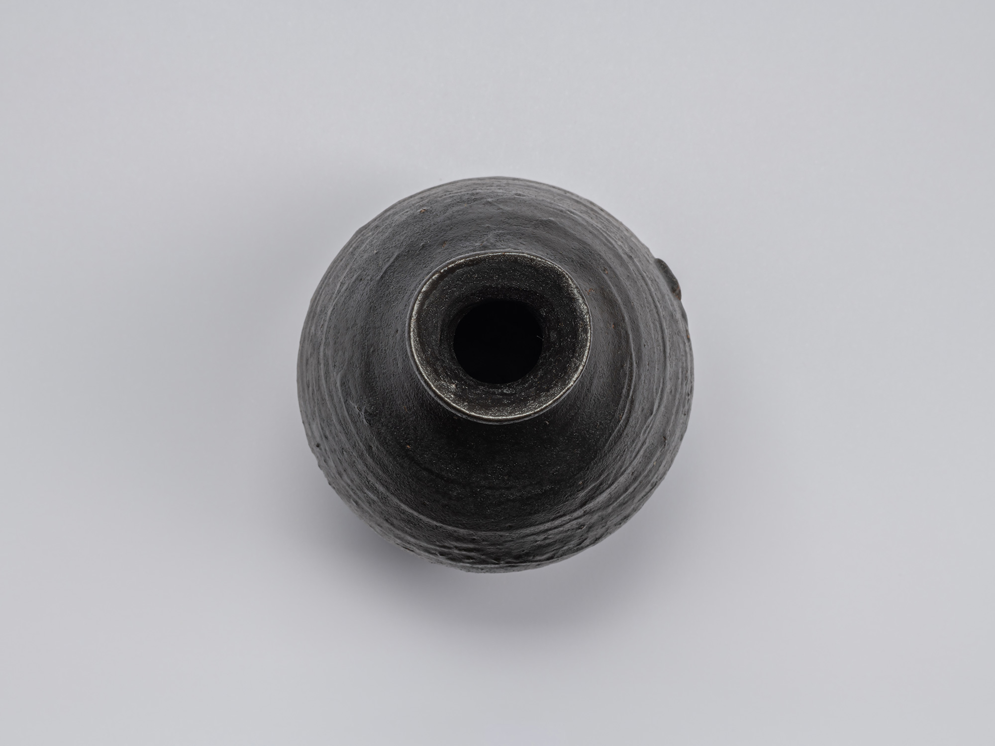 Overhead view of the Kuro Tokkuri by Shiro Tsujimura, showing the irregular rounded mouth, thick...