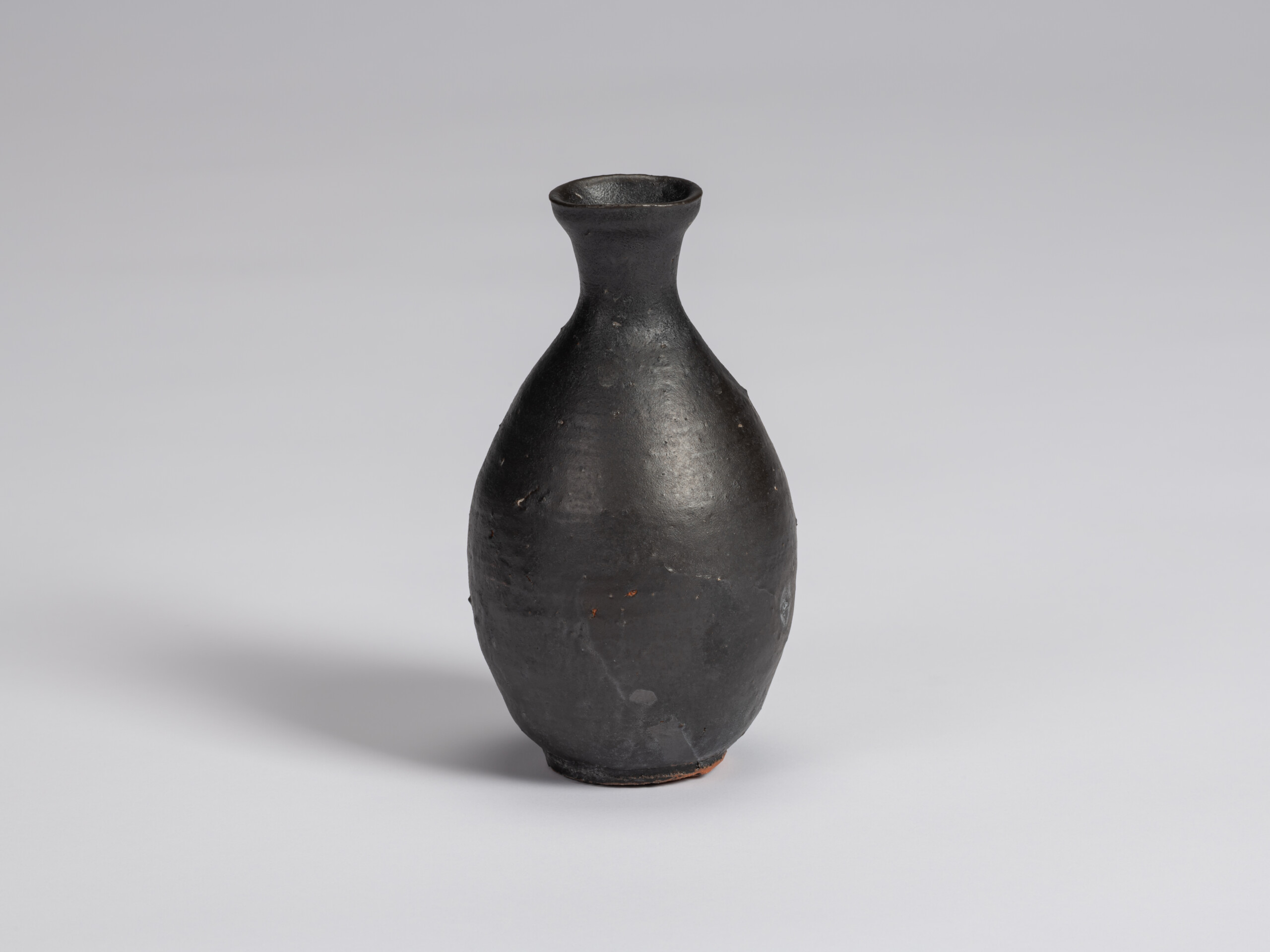 Kuro Tokkuri by Shiro Tsujimura, with a tall oval body, narrow neck, and gently flared irregular...