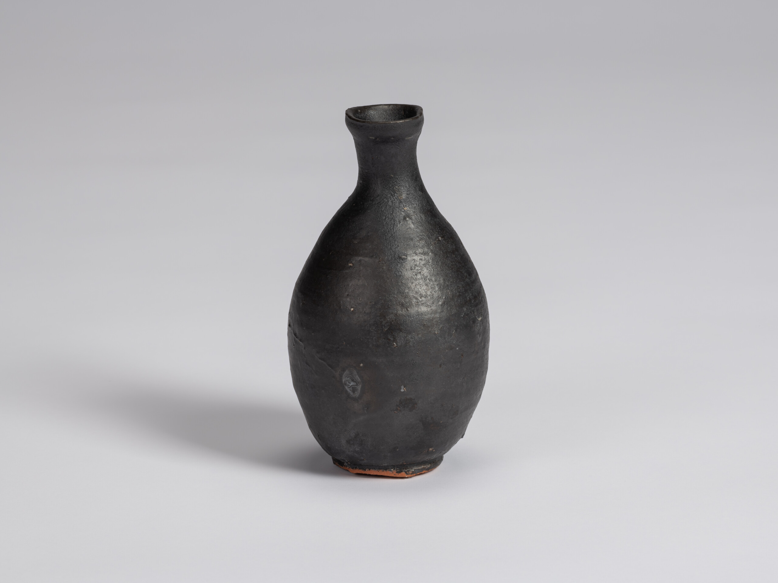 Kuro Tokkuri by Shiro Tsujimura, with a tall oval body, narrow neck, and gently flared irregular...