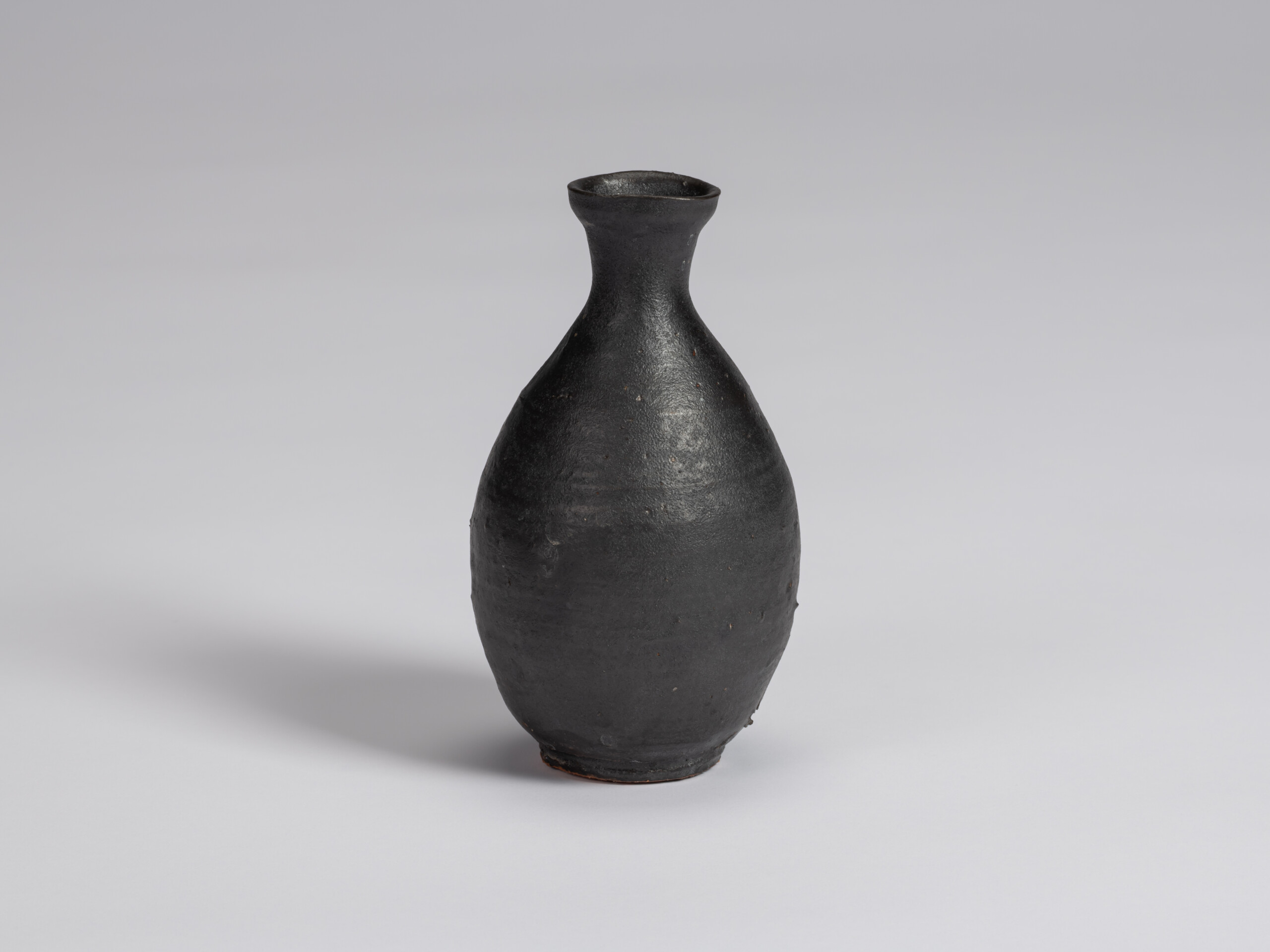 Kuro Tokkuri by Shiro Tsujimura, with a tall oval body, narrow neck, and gently flared irregular...