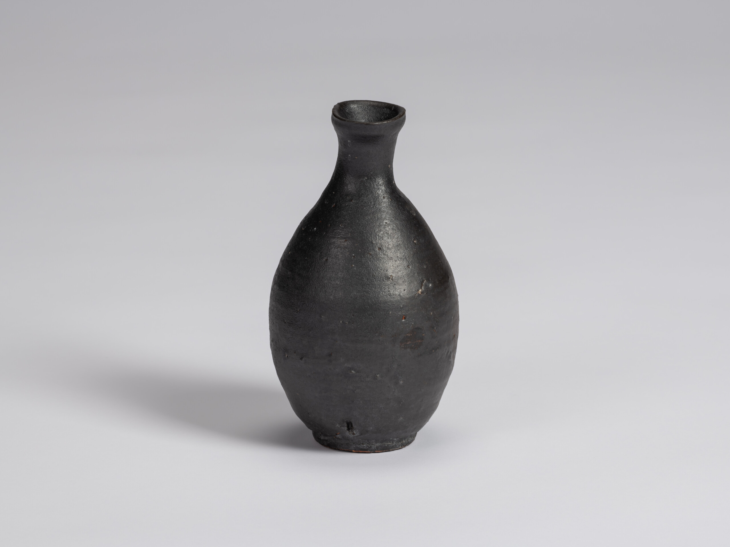 Kuro Tokkuri by Shiro Tsujimura, with a tall oval body, narrow neck, and gently flared irregular...
