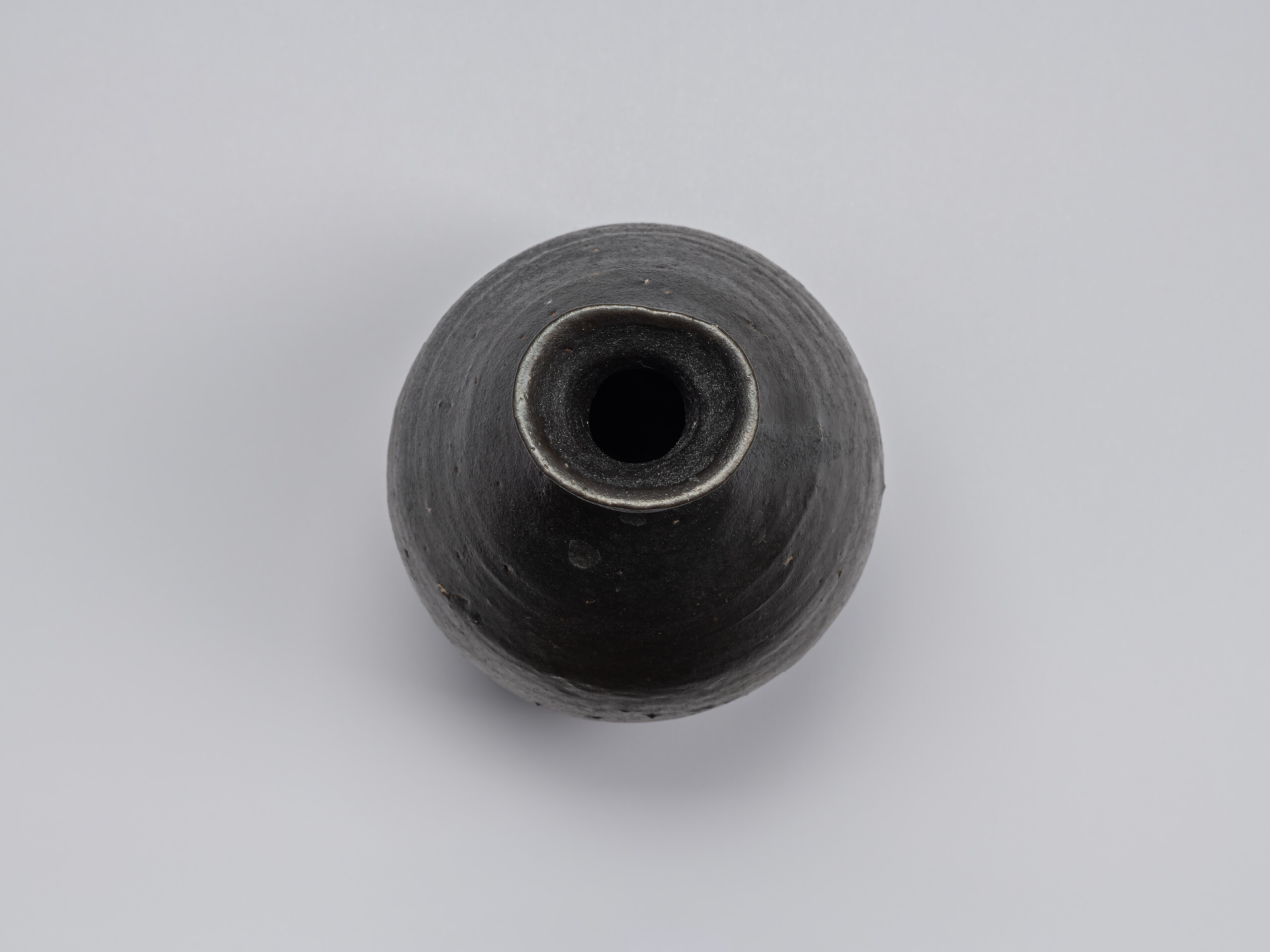 Overhead view of the Kuro Tokkuri by Shiro Tsujimura, showing the irregular oval mouth, thick uneven...