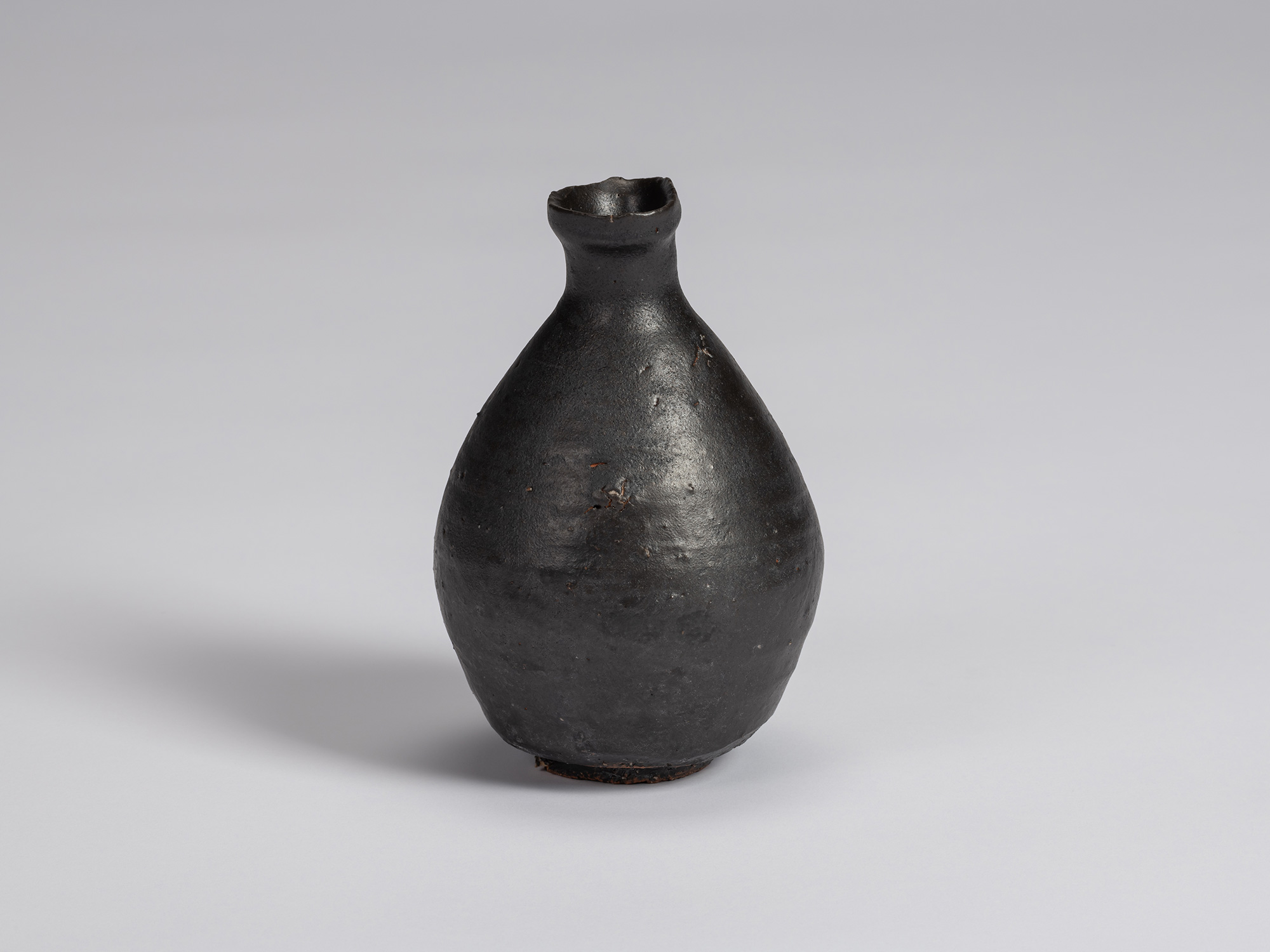 Kuro Tokkuri by Shiro Tsujimura, with a broad rounded body, narrow neck, and irregular flared rim....