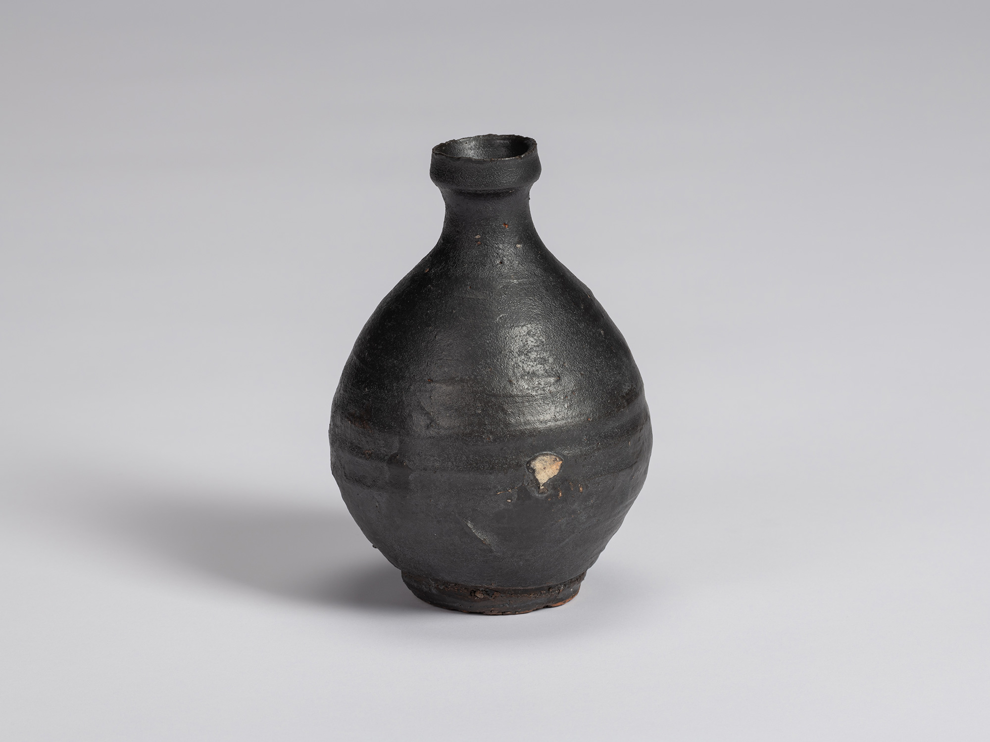 Kuro Tokkuri by Shiro Tsujimura, with a broad rounded body, narrow neck, and irregular flared rim....
