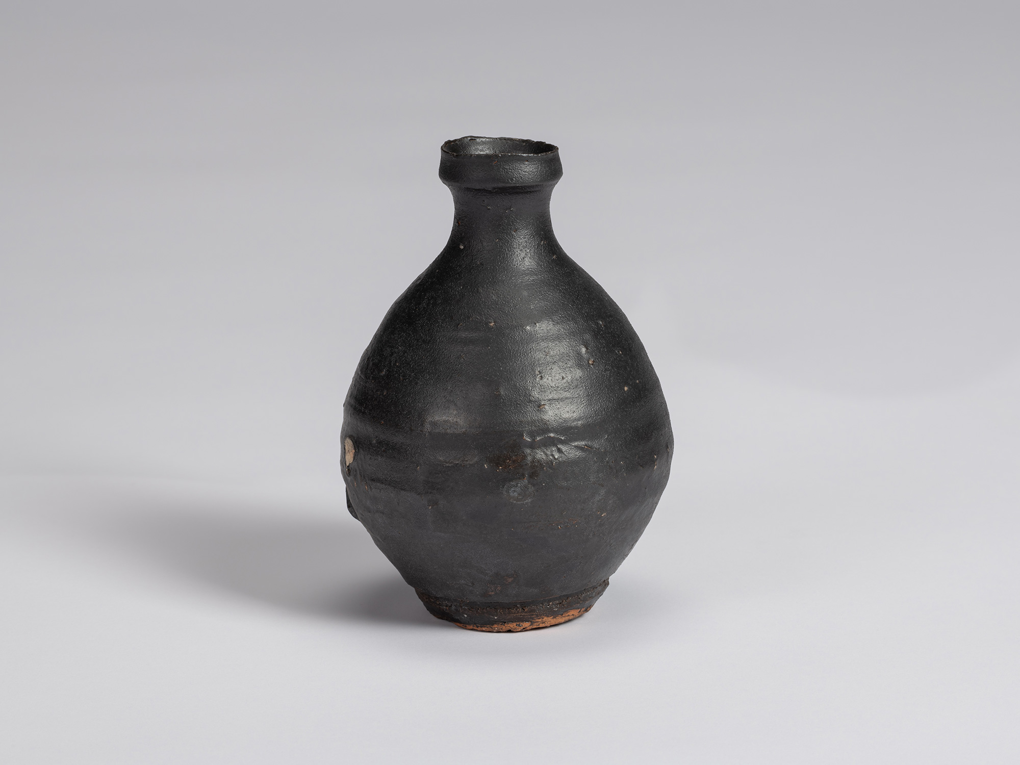 Kuro Tokkuri by Shiro Tsujimura, with a broad rounded body, narrow neck, and irregular flared rim....