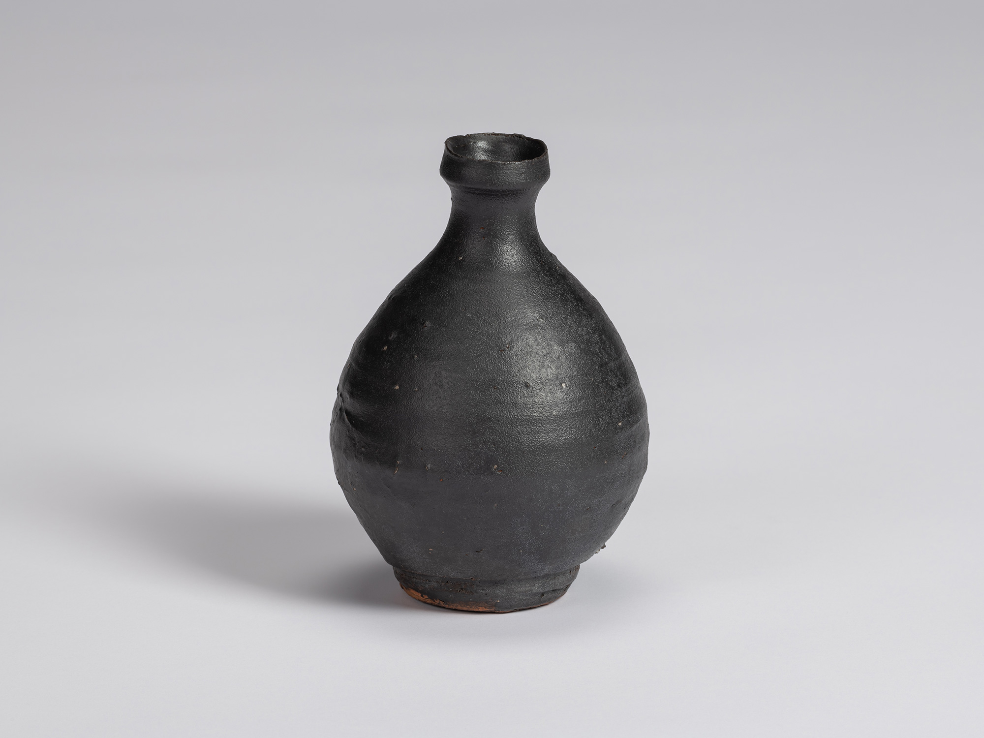 Kuro Tokkuri by Shiro Tsujimura, with a broad rounded body, narrow neck, and irregular flared rim....