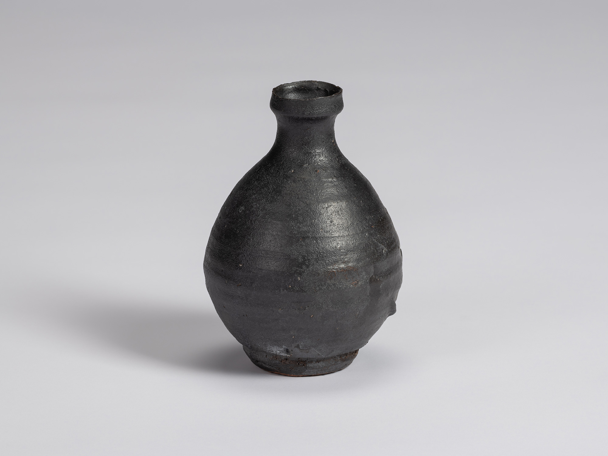 Kuro Tokkuri by Shiro Tsujimura, with a broad rounded body, narrow neck, and irregular flared rim....