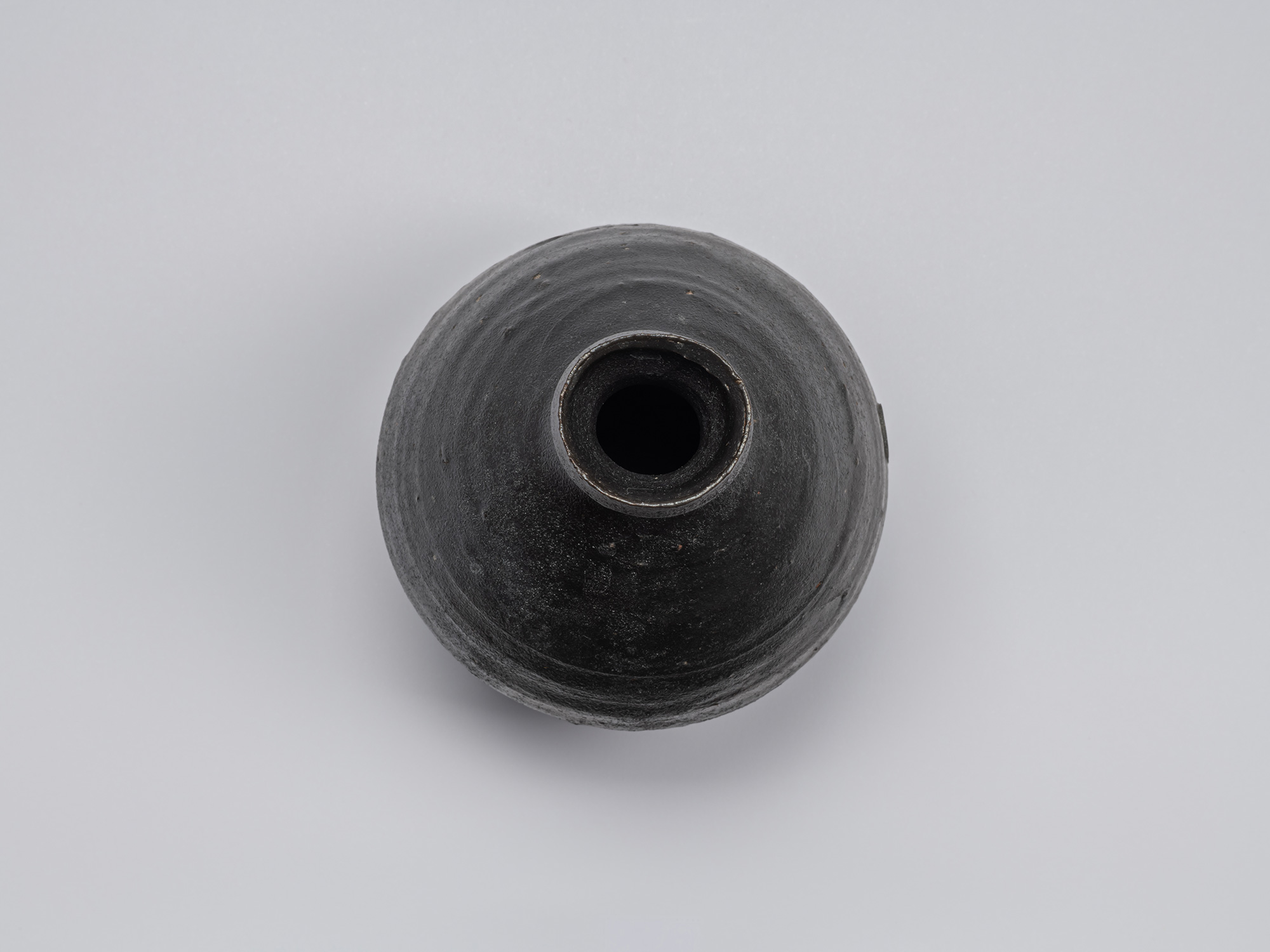 Overhead view of the Kuro Tokkuri by Shiro Tsujimura, showing the rounded mouth, thick irregular...