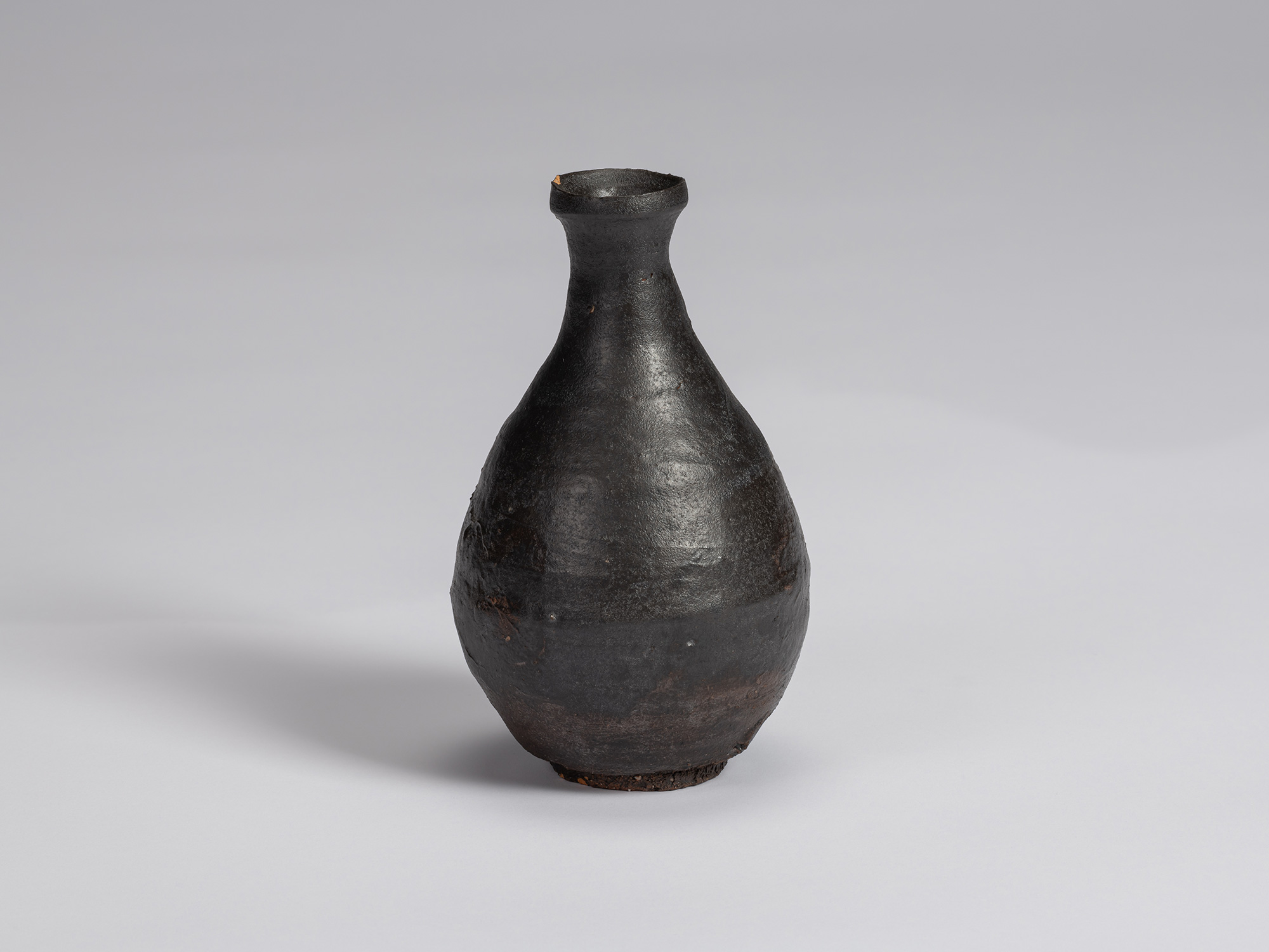 Kuro Tokkuri by Shiro Tsujimura, with a tall pear-shaped body, narrow neck, and irregular flared...