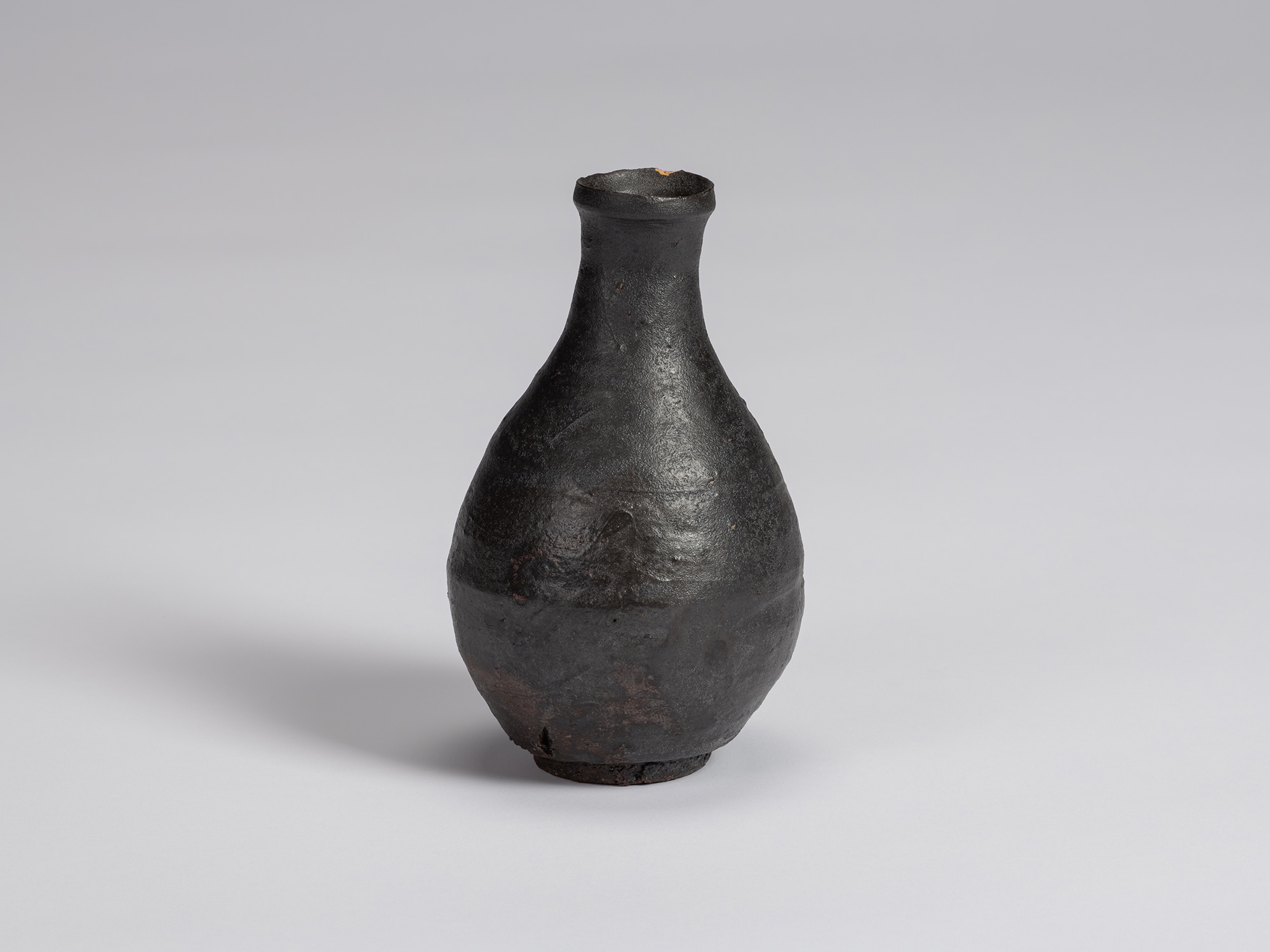 Kuro Tokkuri by Shiro Tsujimura, with a tall pear-shaped body, narrow neck, and irregular flared...