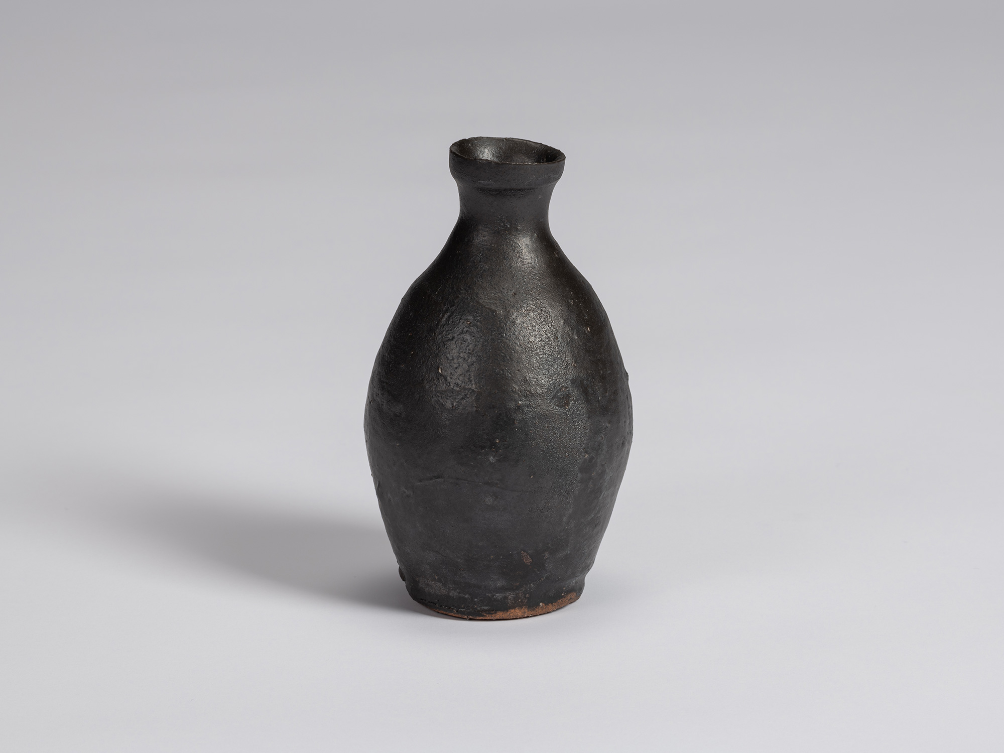 Kuro tokkuri by Shiro Tsujimura with a tall, gently rounded body, sloping shoulders, narrow neck,...