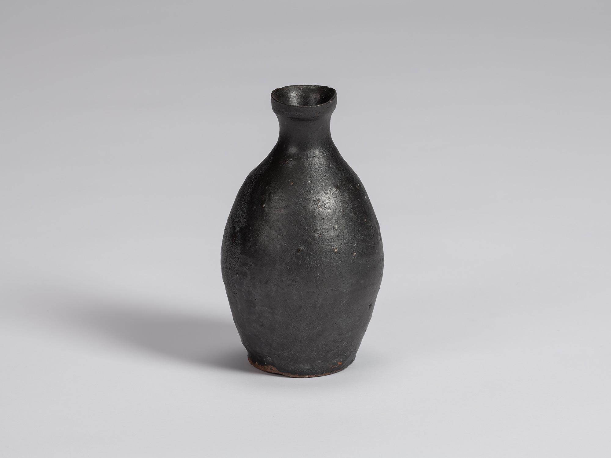 Kuro tokkuri by Shiro Tsujimura with a tall, gently rounded body, sloping shoulders, narrow neck,...