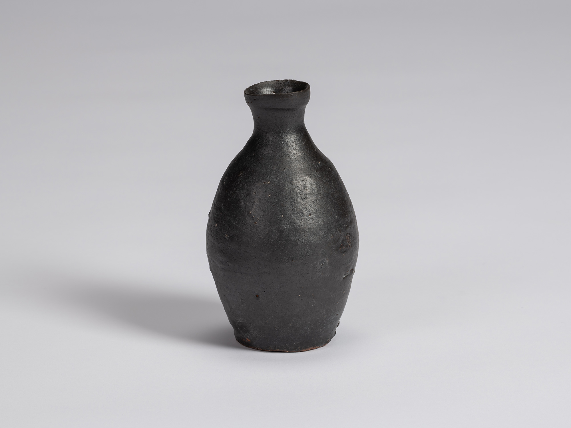 Kuro tokkuri by Shiro Tsujimura with a tall, gently rounded body, sloping shoulders, narrow neck,...