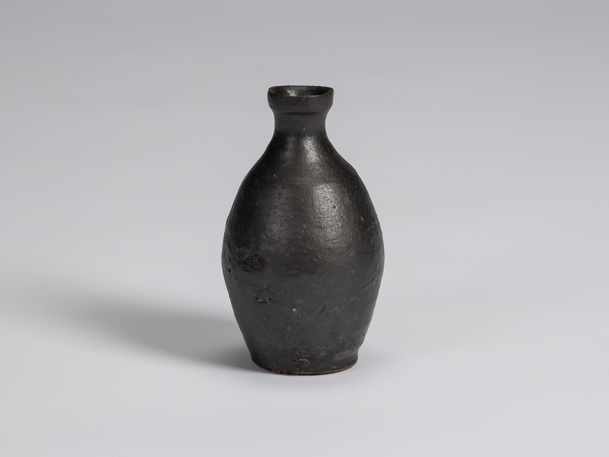 Kuro tokkuri by Shiro Tsujimura with a tall, gently rounded body, sloping shoulders, narrow neck,...