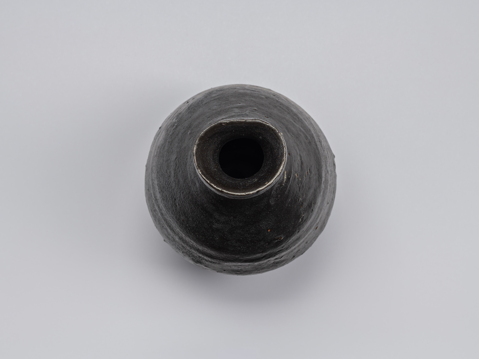 Overhead view of the Kuro Tokkuri by Shiro Tsujimura, showing the irregular rounded mouth, thick...