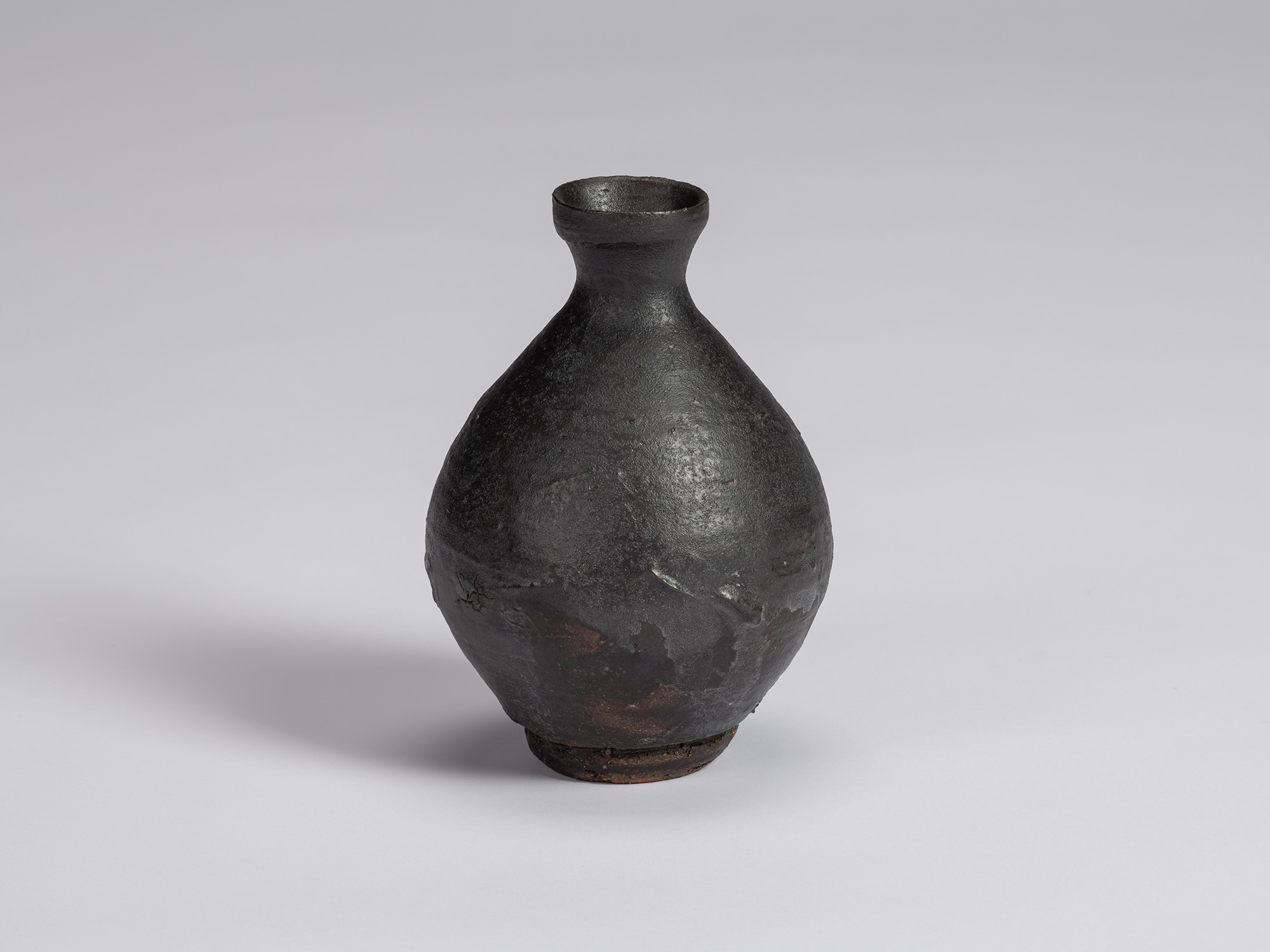 Kuro tokkuri by Shiro Tsujimura with a broad, pear-shaped body, sloping shoulders, narrow neck,...