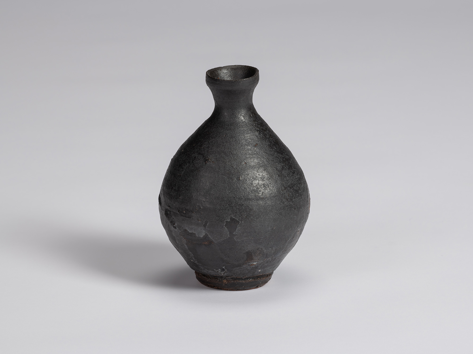 Kuro tokkuri by Shiro Tsujimura with a broad, pear-shaped body, sloping shoulders, narrow neck,...