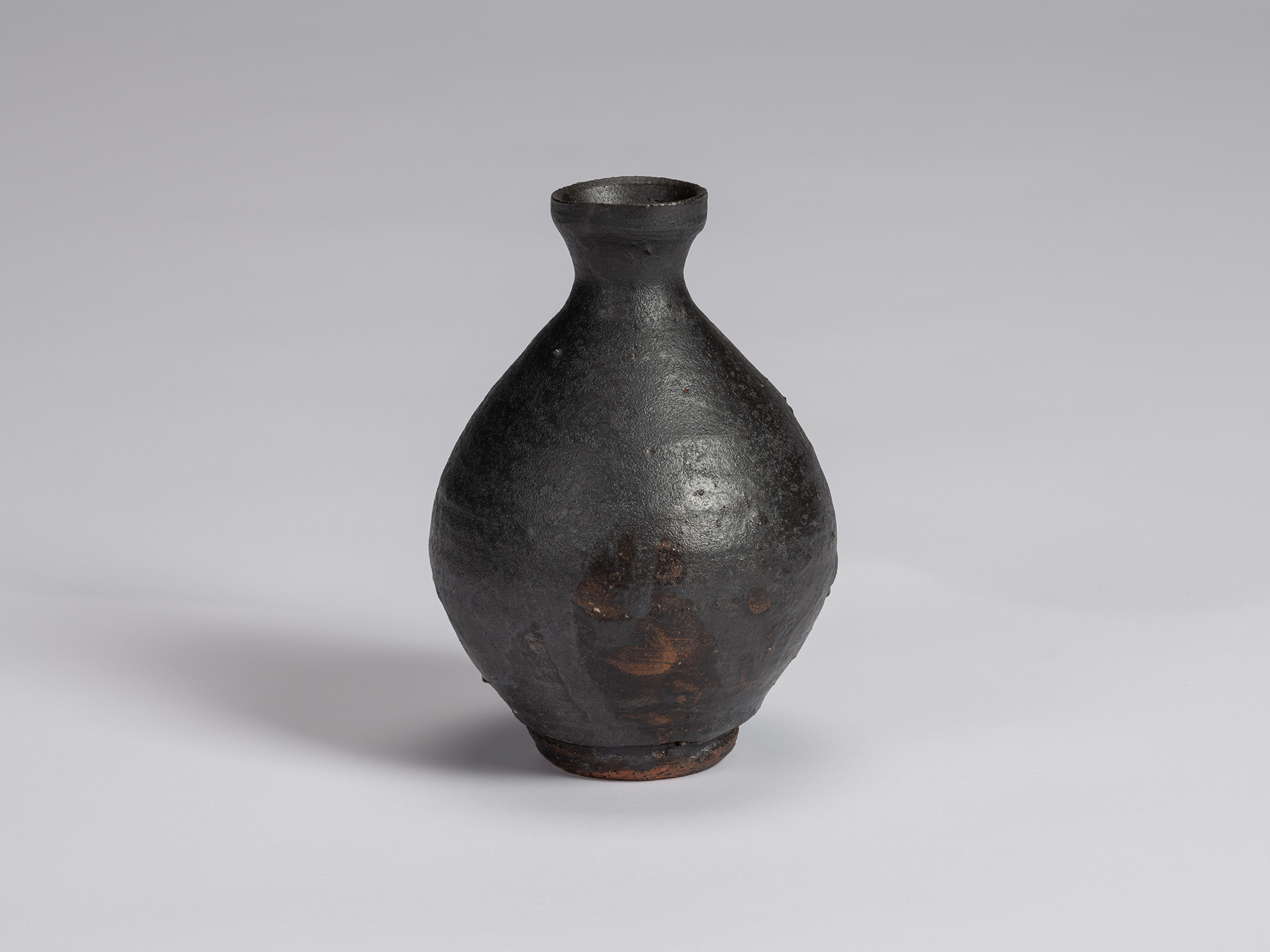 Kuro tokkuri by Shiro Tsujimura with a broad, pear-shaped body, sloping shoulders, narrow neck,...