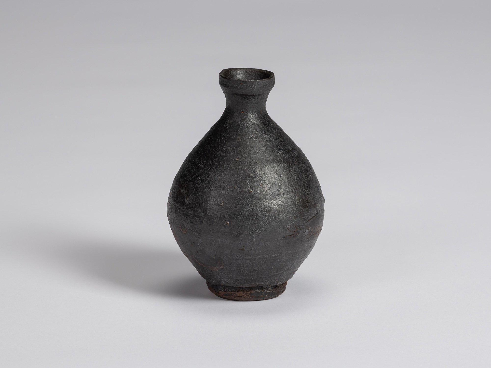Kuro tokkuri by Shiro Tsujimura with a broad, pear-shaped body, sloping shoulders, narrow neck,...