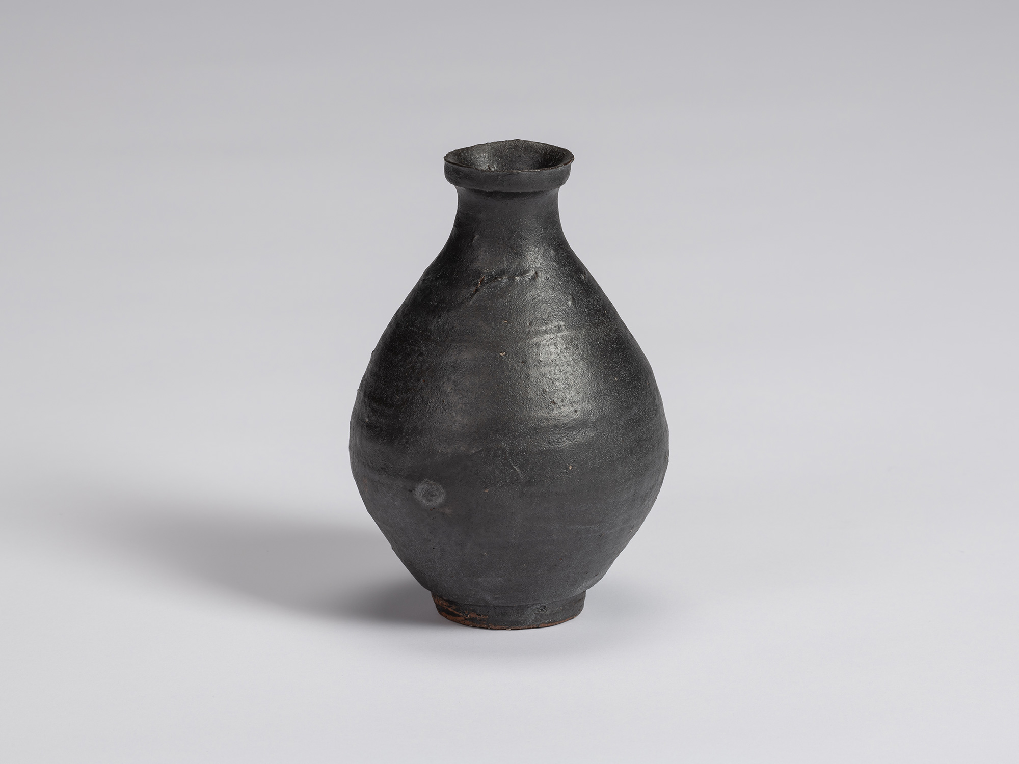 Kuro Tokkuri by Shiro Tsujimura with a rounded, full-bodied form, narrow neck, flared irregular...