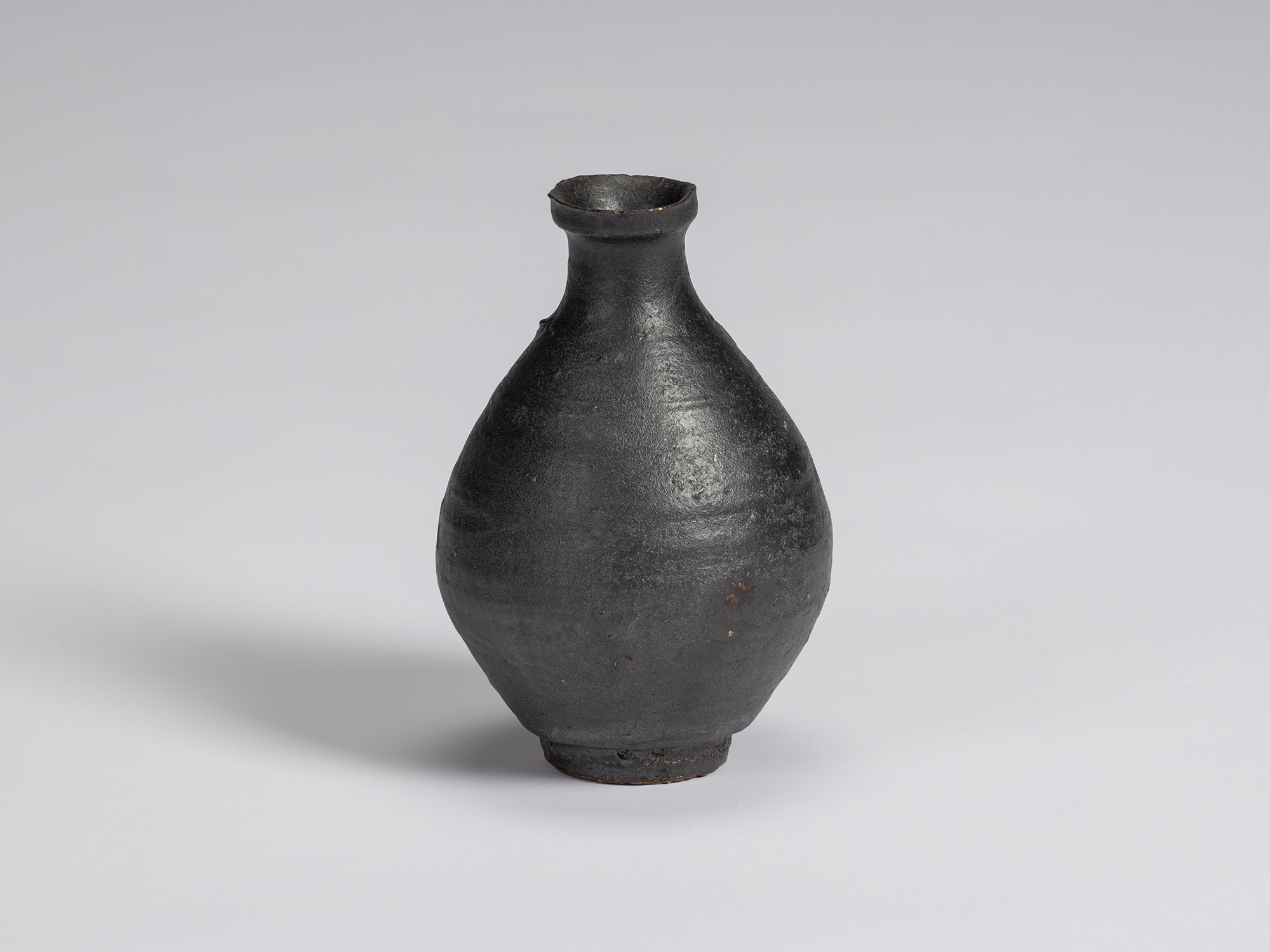 Kuro Tokkuri by Shiro Tsujimura with a rounded, full-bodied form, narrow neck, flared irregular...