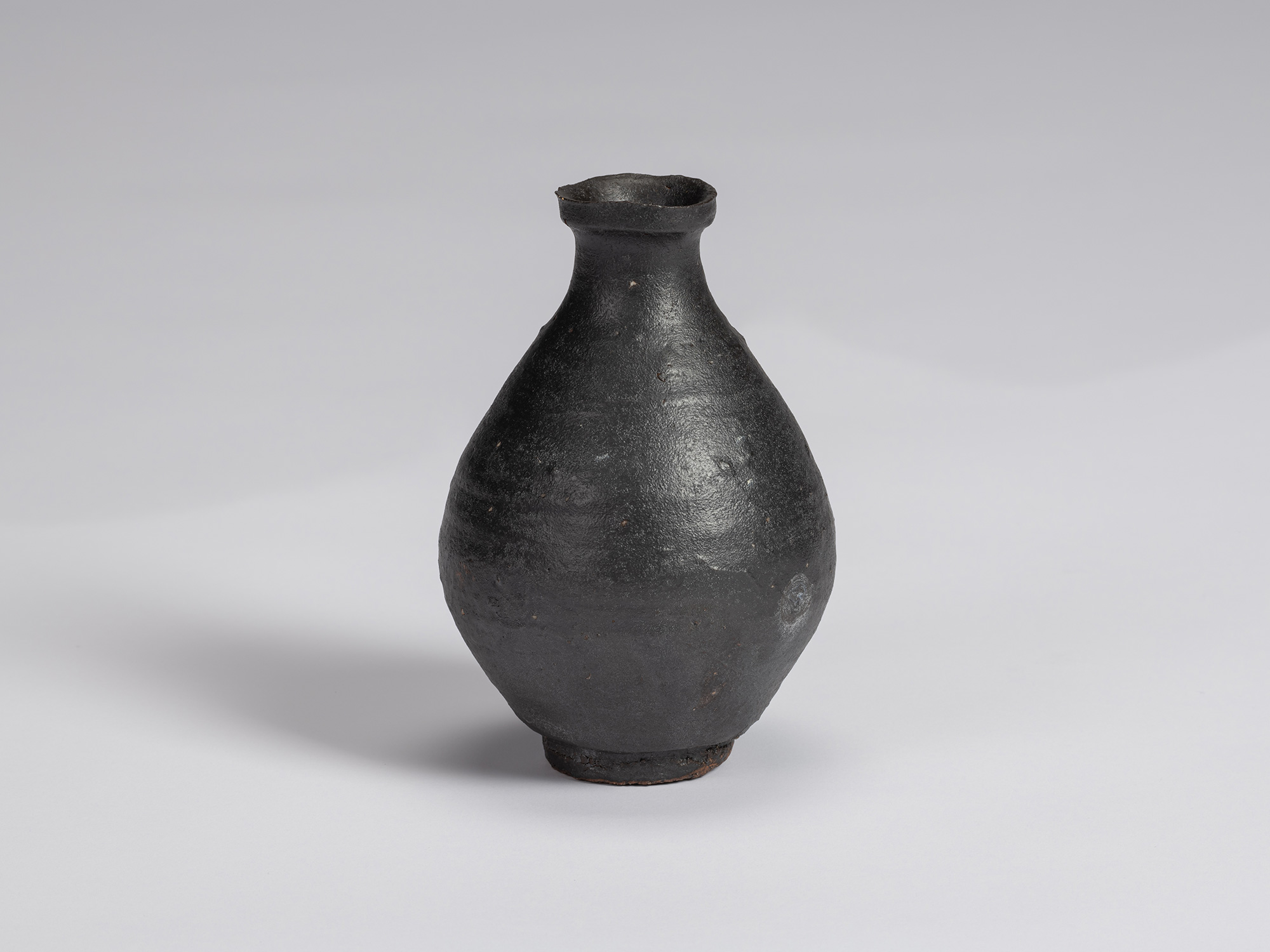Kuro Tokkuri by Shiro Tsujimura with a rounded, full-bodied form, narrow neck, flared irregular...