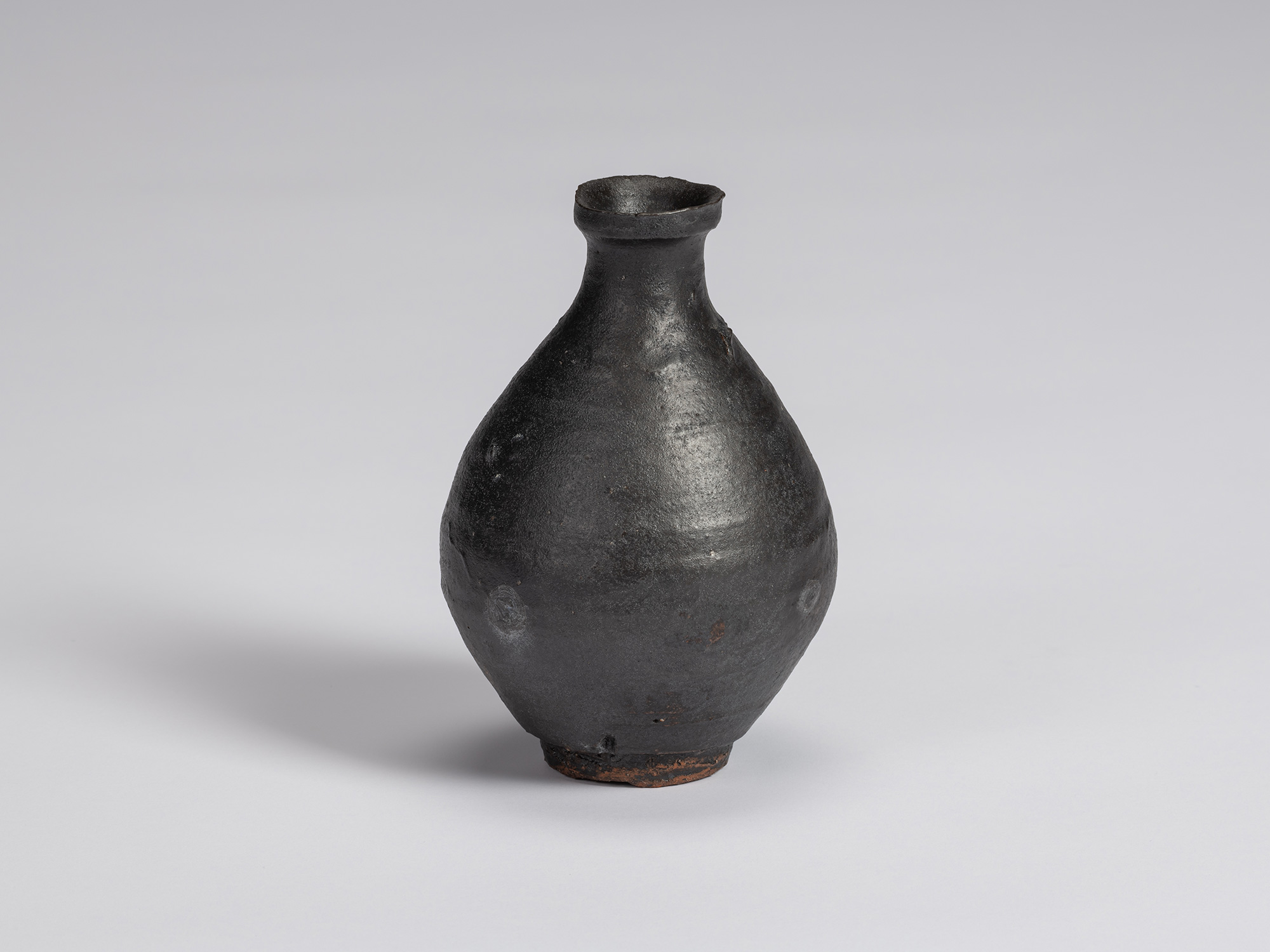 Kuro Tokkuri by Shiro Tsujimura with a rounded, full-bodied form, narrow neck, flared irregular...