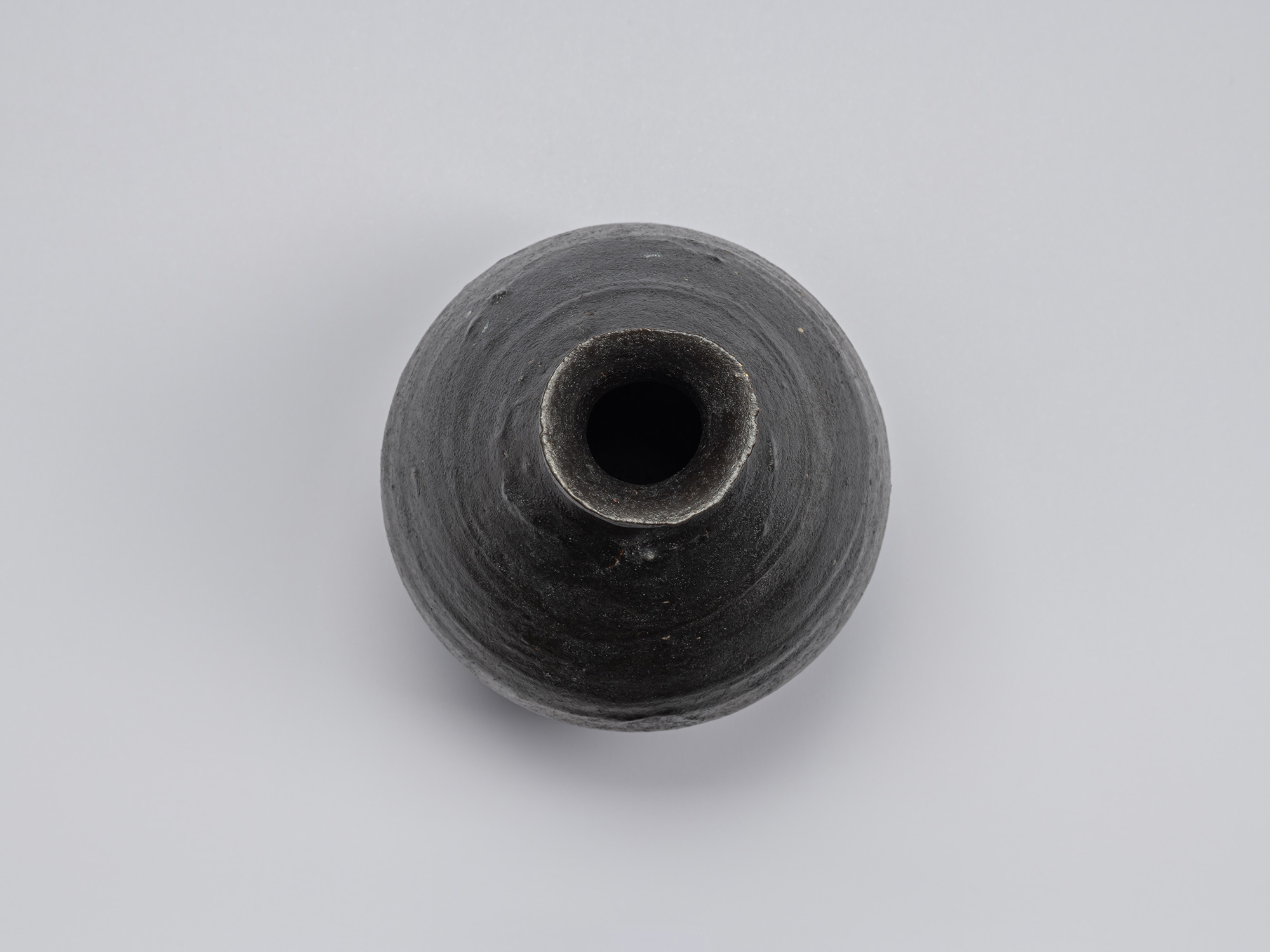 Overhead view of Shiro Tsujimura’s Kuro Tokkuri, showing the narrow circular opening, irregular...