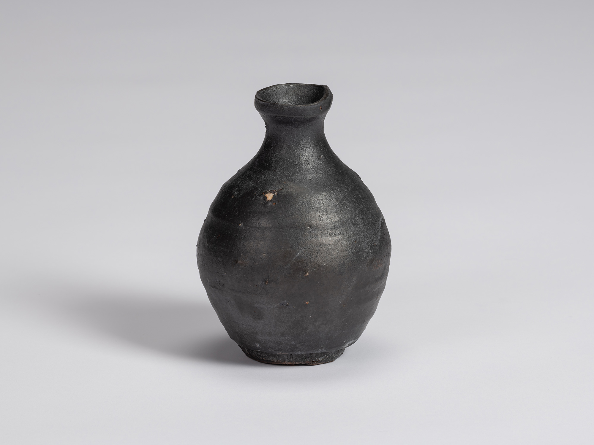 Shiro Tsujimura’s Kuro Tokkuri, highlighting a prominent patch of exposed pale clay against the...