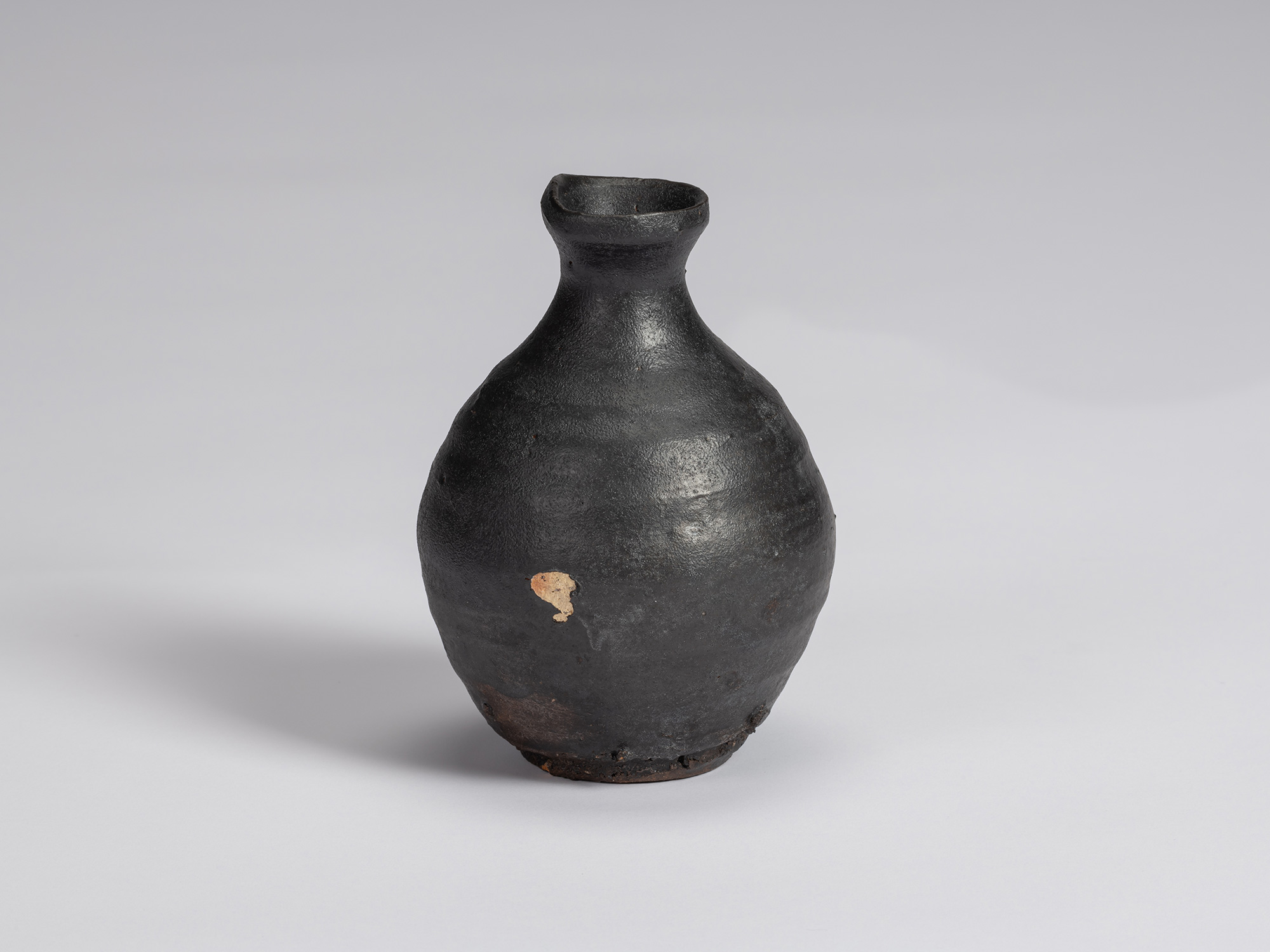 Shiro Tsujimura’s Kuro Tokkuri, highlighting a prominent patch of exposed pale clay against the...