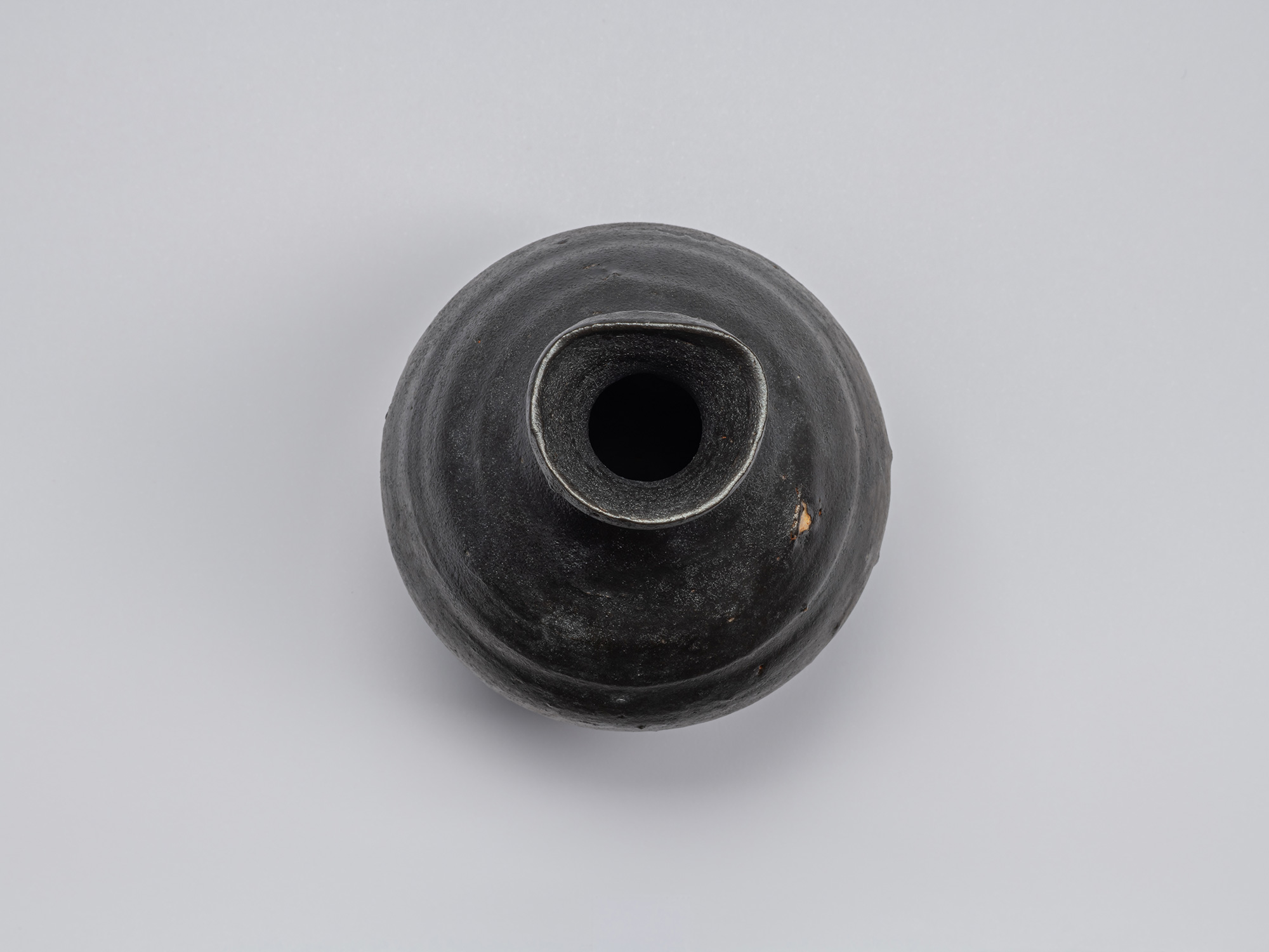 Overhead view of Shiro Tsujimura’s Kuro Tokkuri, showing the narrow circular opening, irregular...