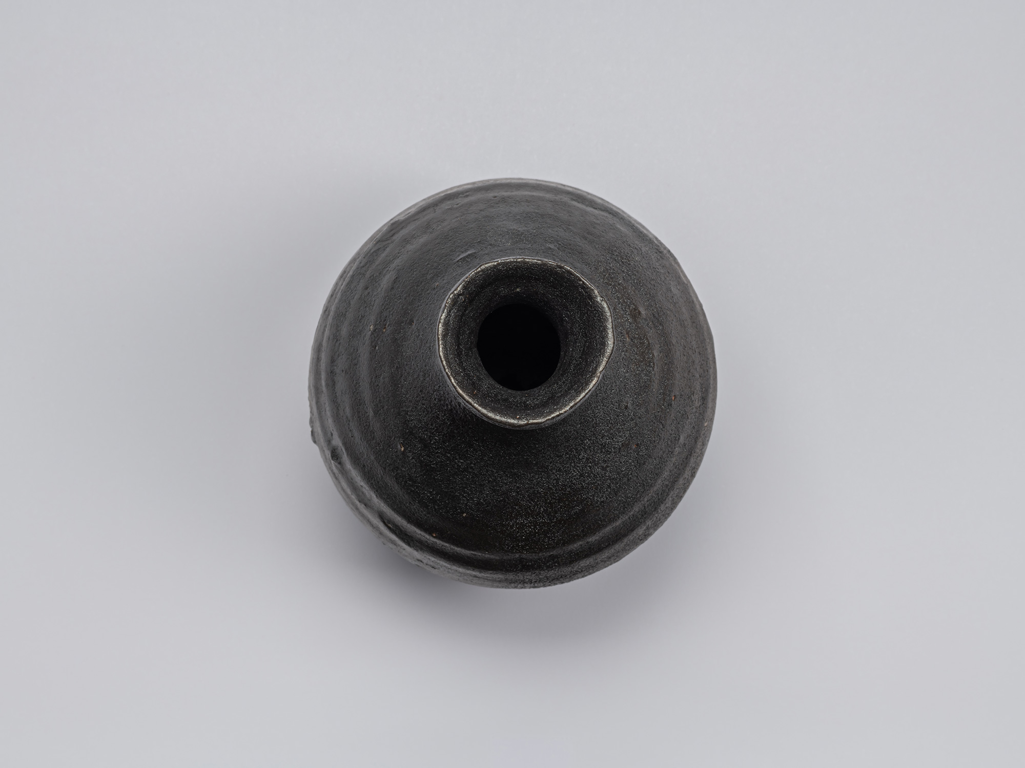 Overhead view of Shiro Tsujimura’s Kuro Tokkuri, showing the narrow circular opening, irregular...