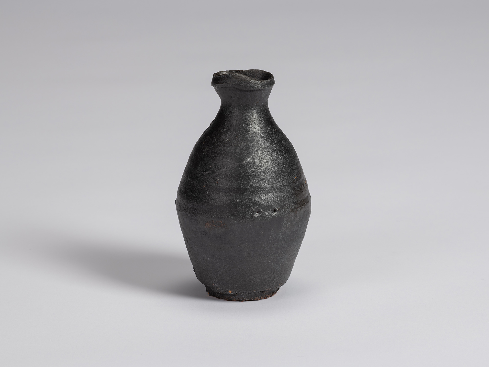 Kuro Tokkuri by Shiro Tsujimura with a tall, slightly asymmetrical body, tapered shoulders, narrow...