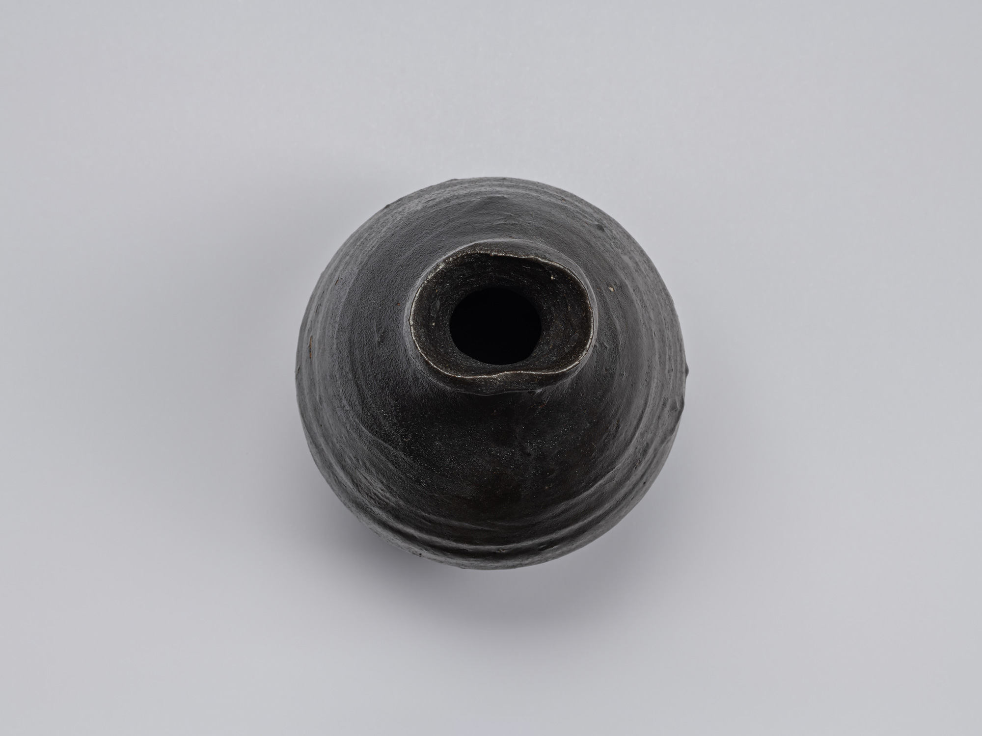 Overhead view of Shiro Tsujimura’s Kuro Tokkuri, showing the narrow circular opening, irregular...