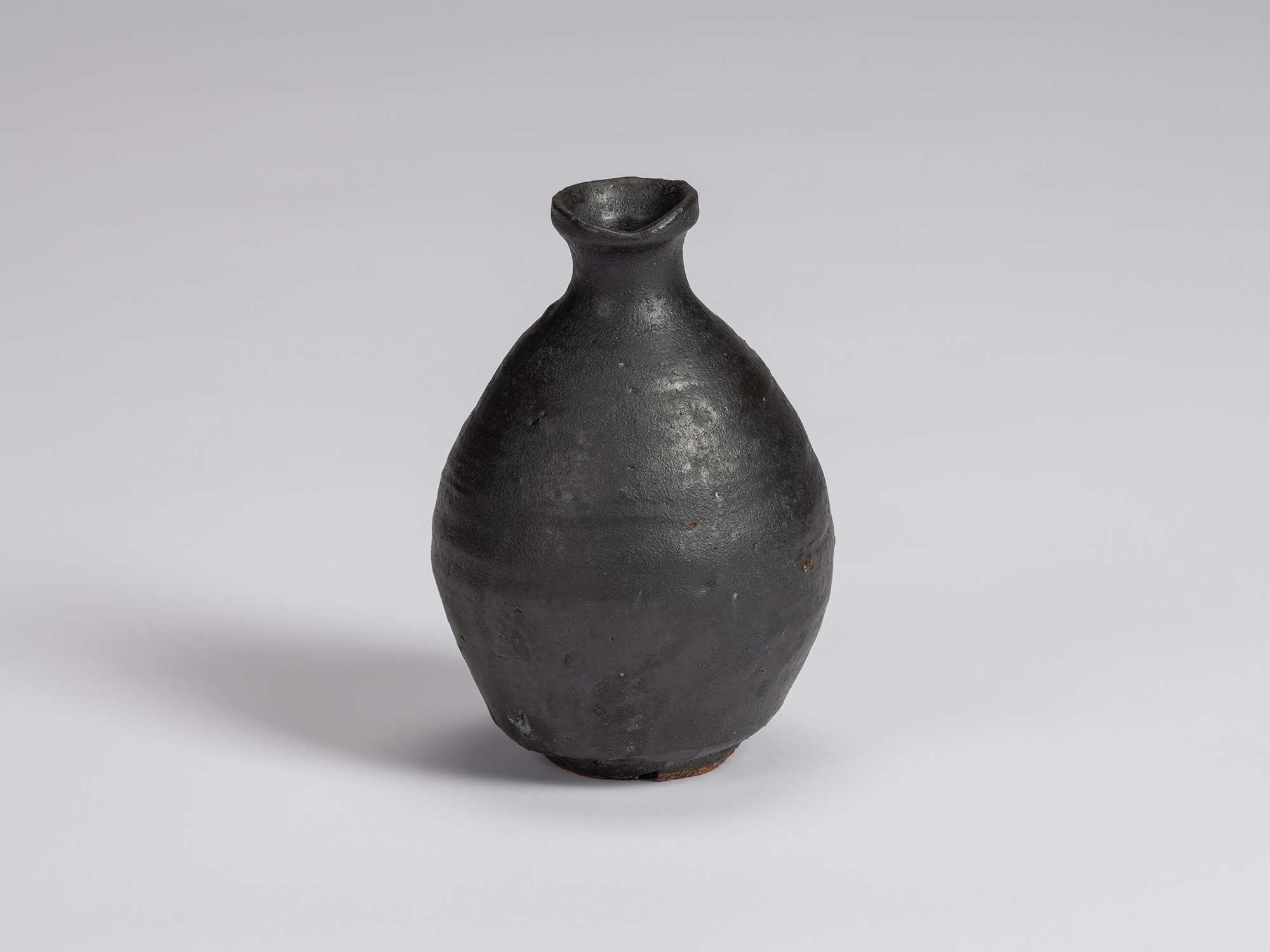 Kuro Tokkuri by Shiro Tsujimura with a rounded, slightly asymmetrical body, sloping shoulders,...