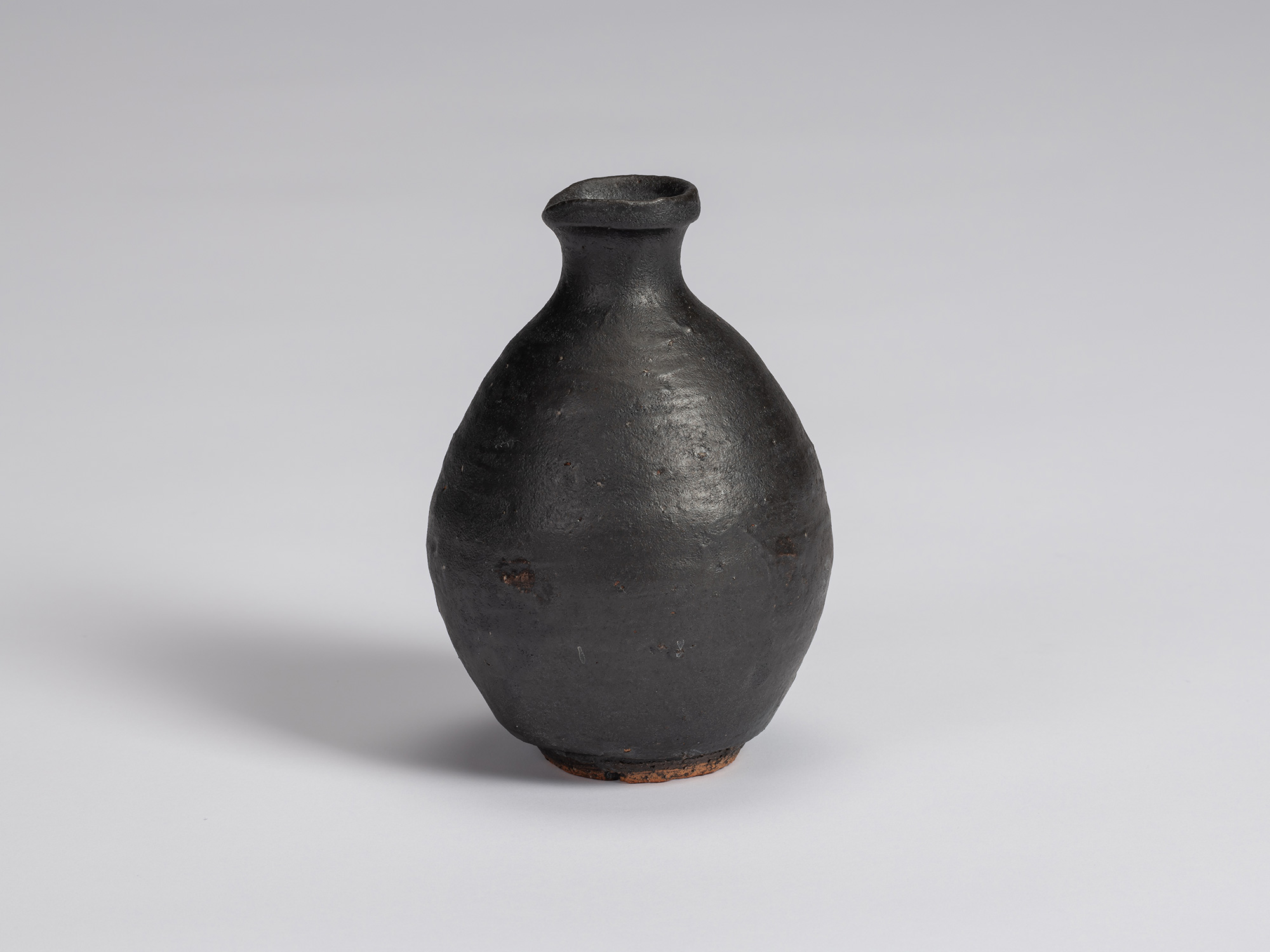 Kuro Tokkuri by Shiro Tsujimura with a rounded, slightly asymmetrical body, sloping shoulders,...