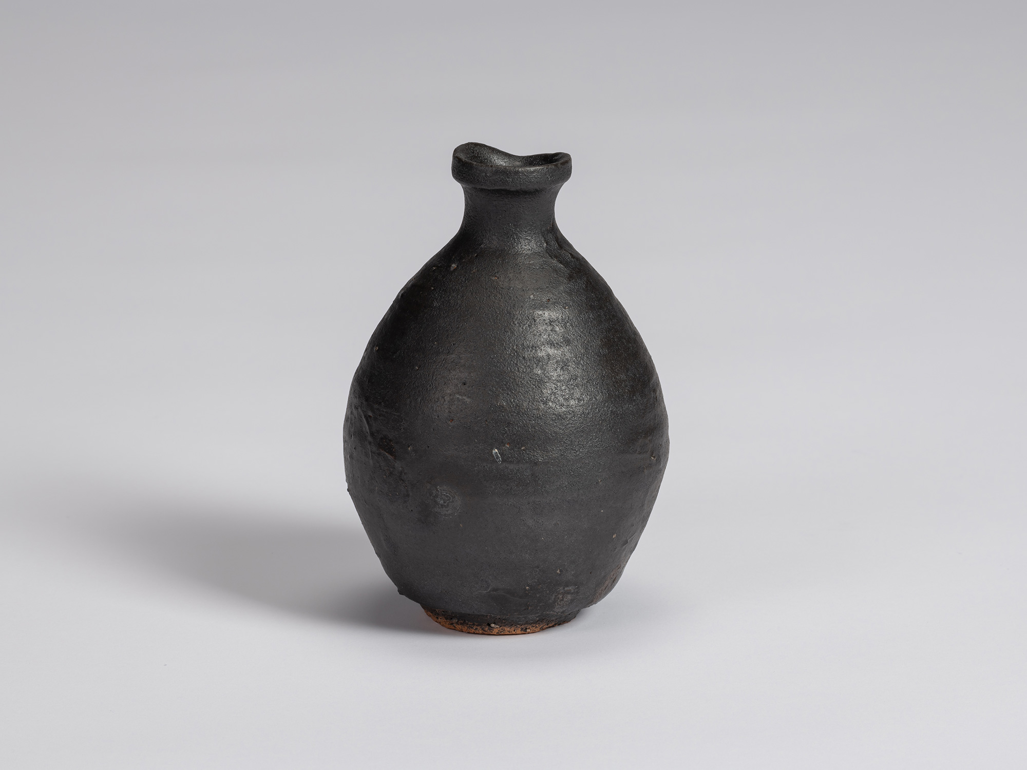 Kuro Tokkuri by Shiro Tsujimura with a rounded, slightly asymmetrical body, sloping shoulders,...