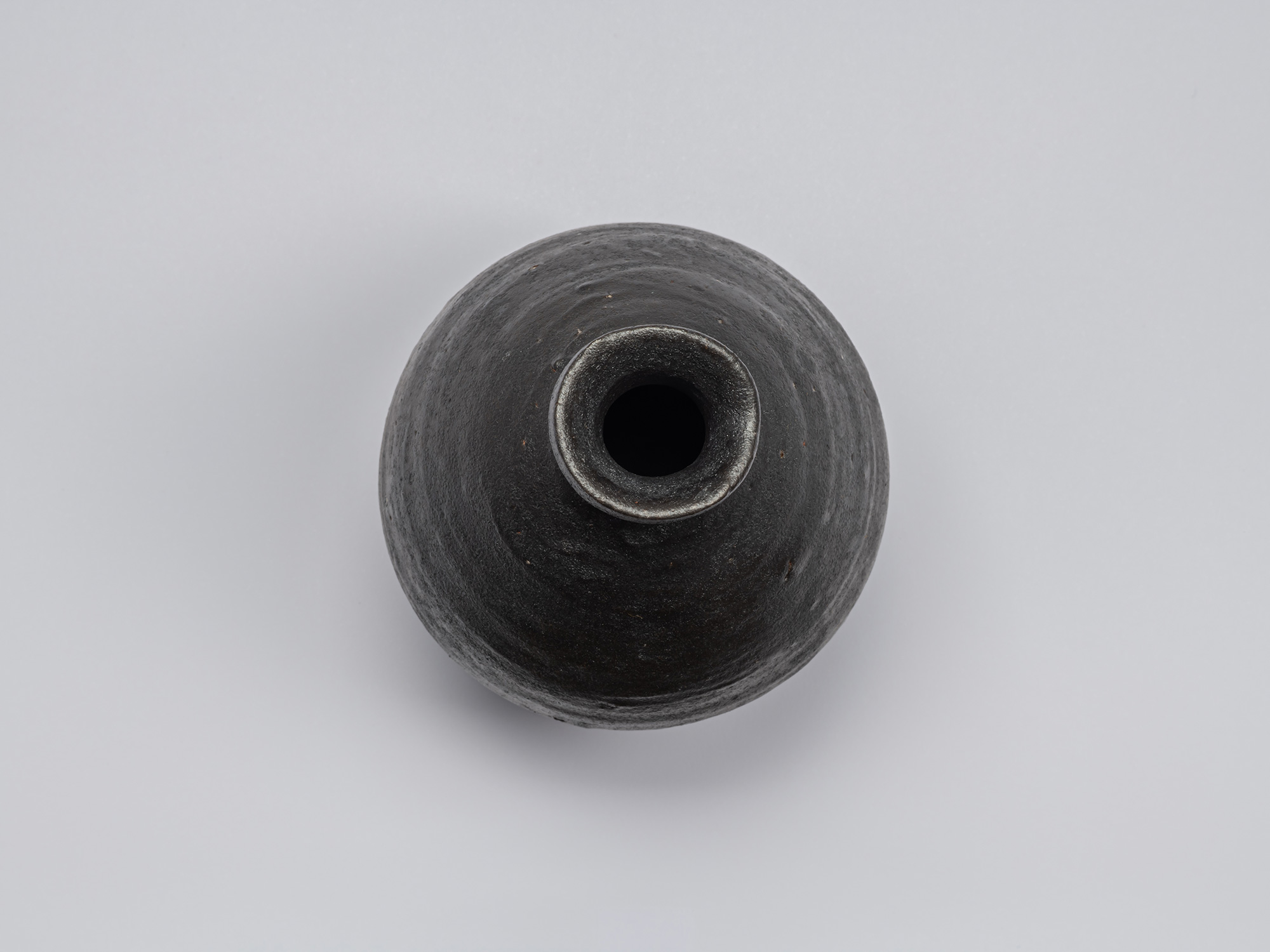 Overhead view of Shiro Tsujimura’s Kuro Tokkuri, showing the narrow circular opening, irregular...