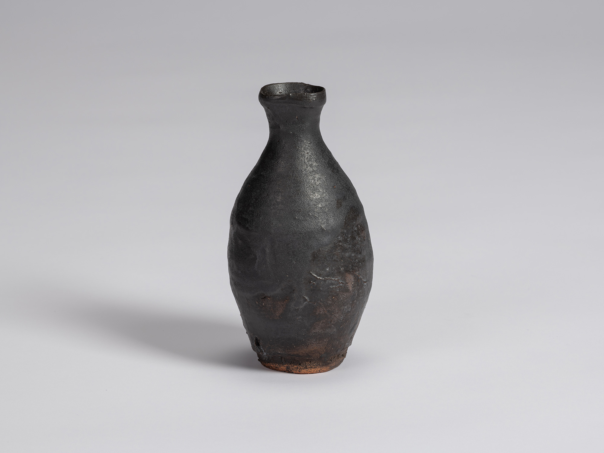 Kuro Tokkuri by Shiro Tsujimura, with a rounded, asymmetrical body, narrow neck, and irregular...