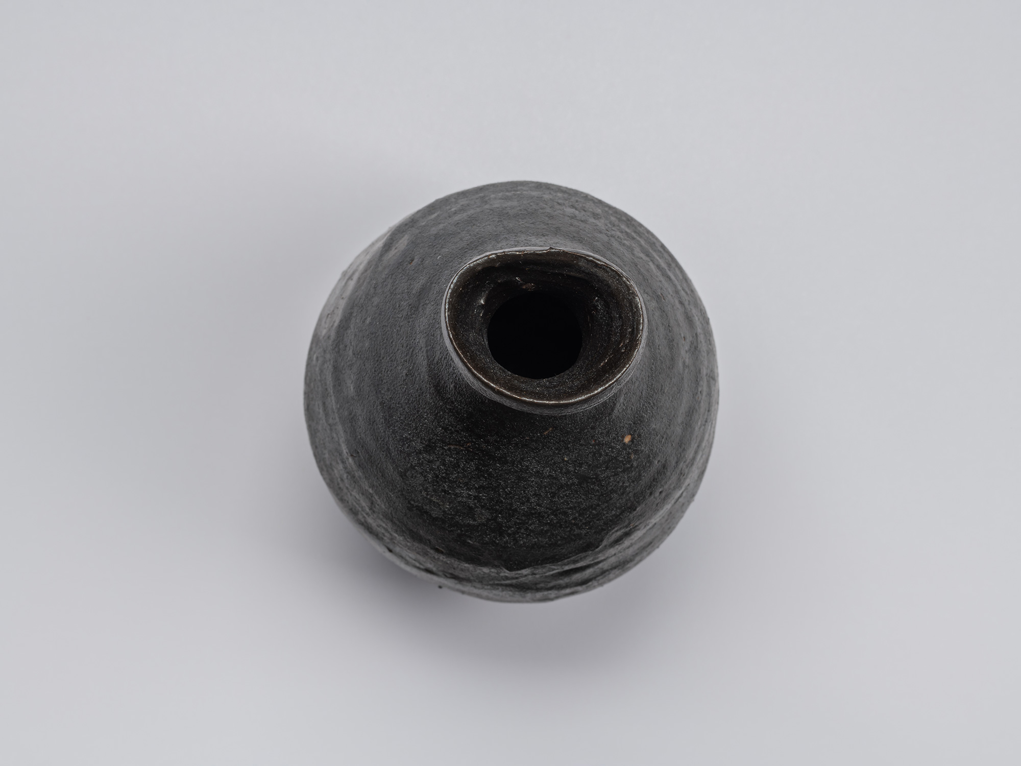 Overhead view of the Kuro Tokkuri by Shiro Tsujimura, showing the irregular oval mouth, thick uneven...