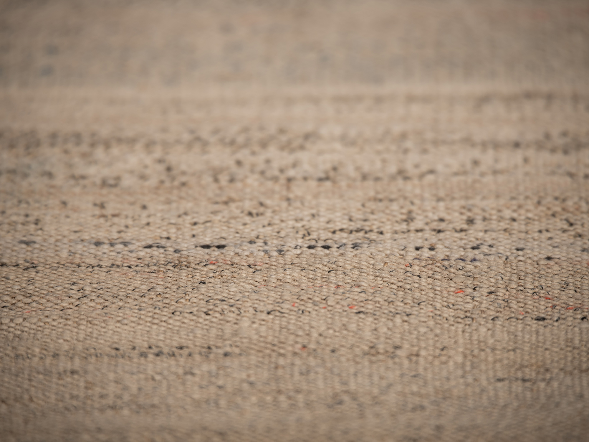Close-up of otsuzure fabric highlighting its uneven handwoven texture, natural beige fibers interspersed...