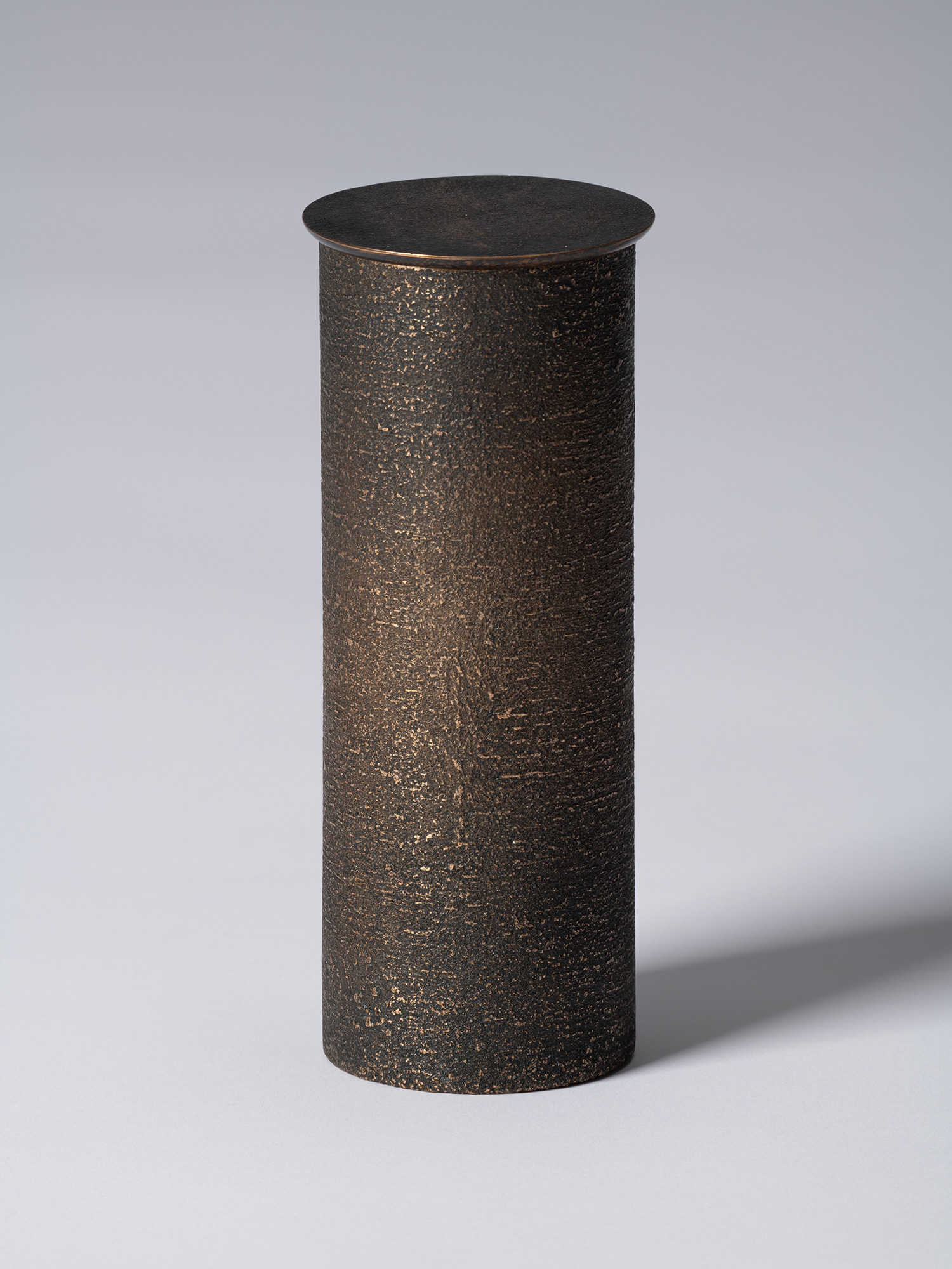 bronze as Bronze II No. 14 by Koji Hatakeyama, a tall cylindrical bronze vessel with a fitted circular...