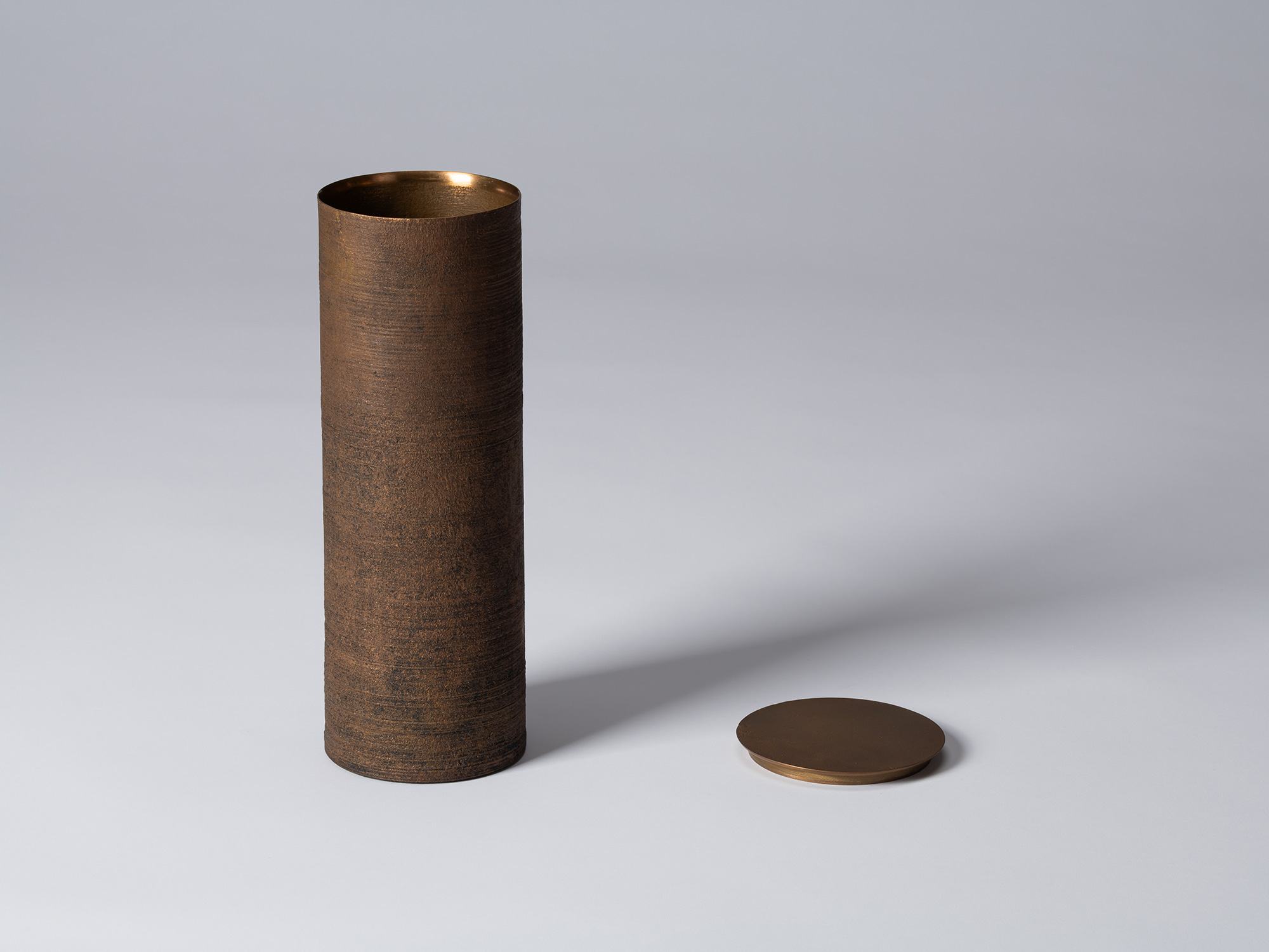 Bronze as Bronze II No. 27 shown with its lid removed, revealing the warm bronze interior; the...