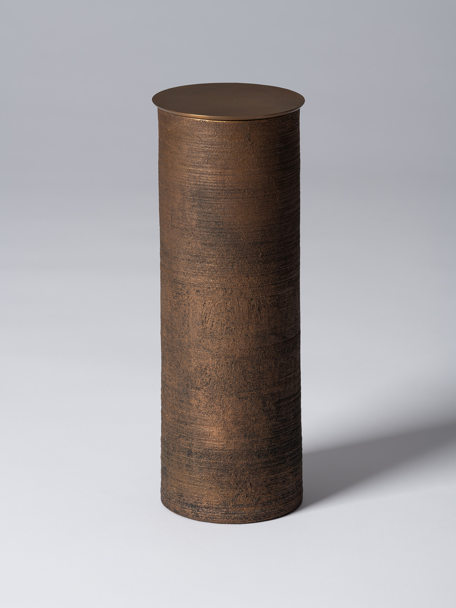 Bronze as Bronze II No. 28 by Koji Hatakeyama, a tall cylindrical lidded vessel with a dark brown...