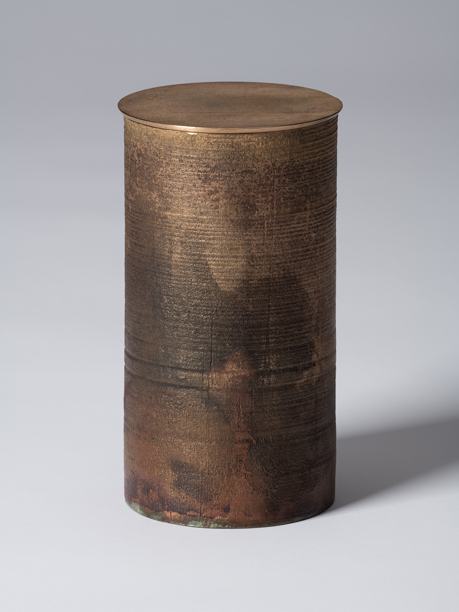 Alternate view of the lidded bronze vessel, showing the cylindrical form and textured exterior...