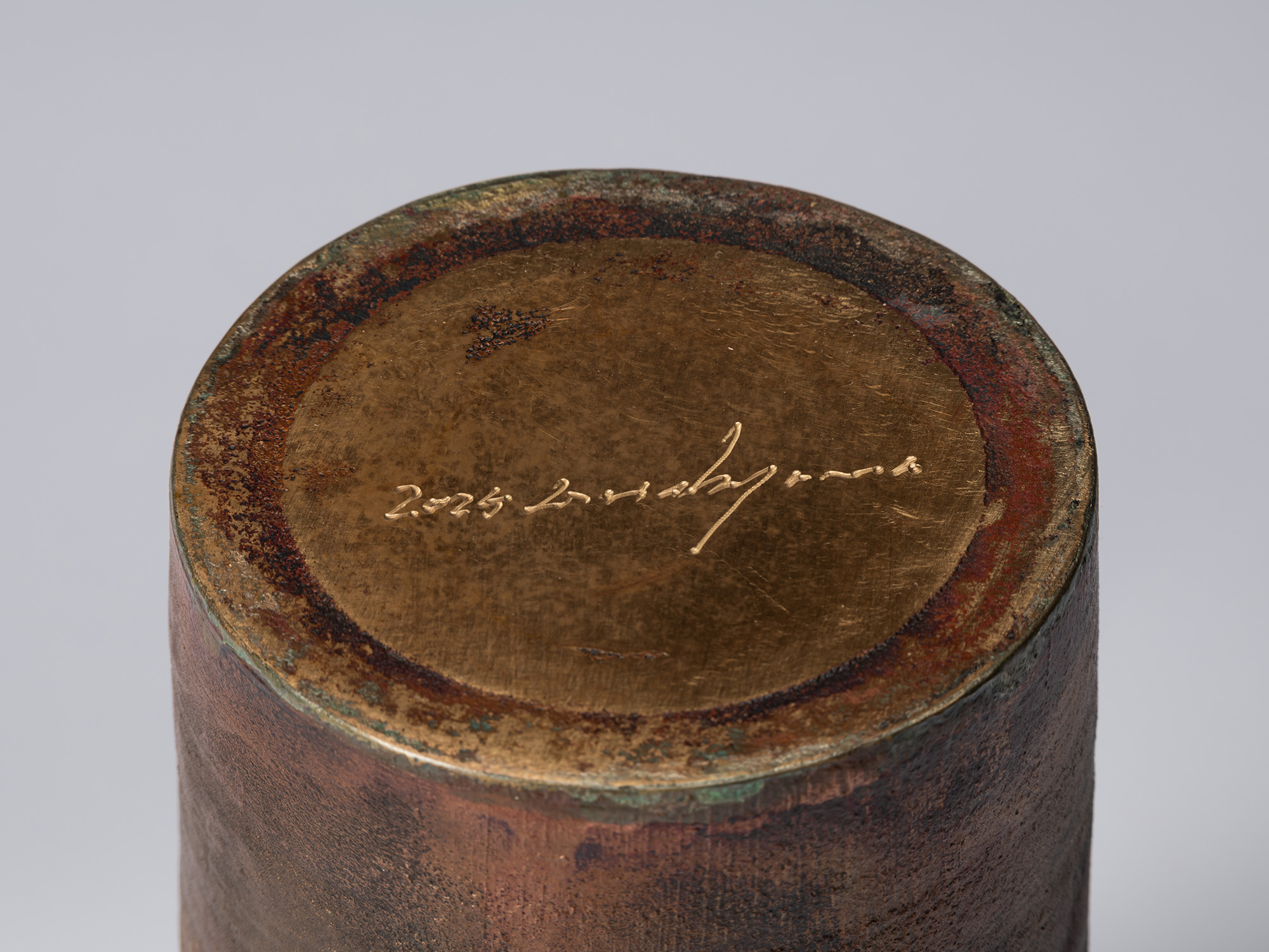 Detail of the underside of the bronze vessel, showing a circular base with the artist’s incised...