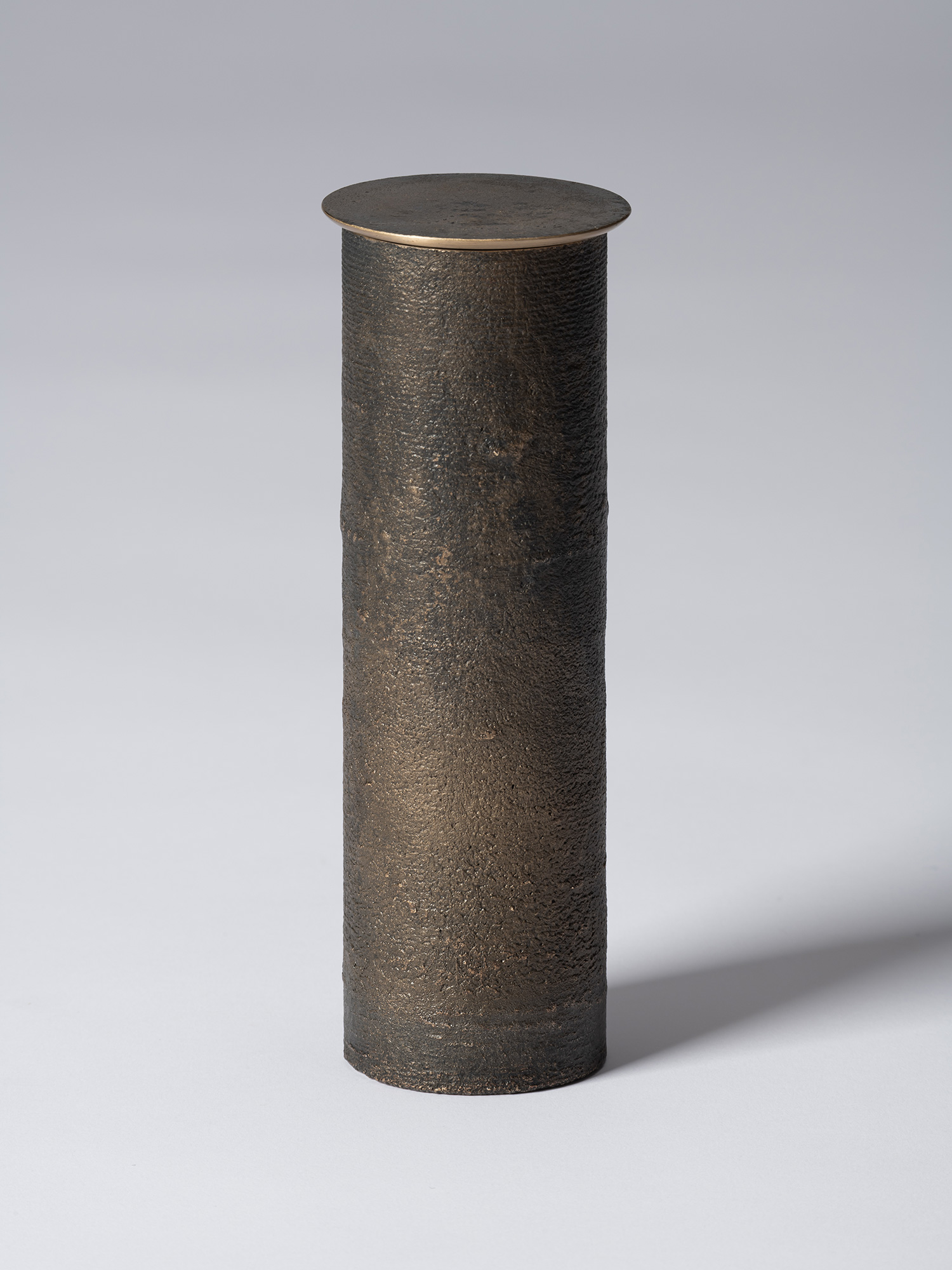 Front view of bronze as Bronze II No. 31 by Koji Hatakeyama, a tall cylindrical bronze vessel with...
